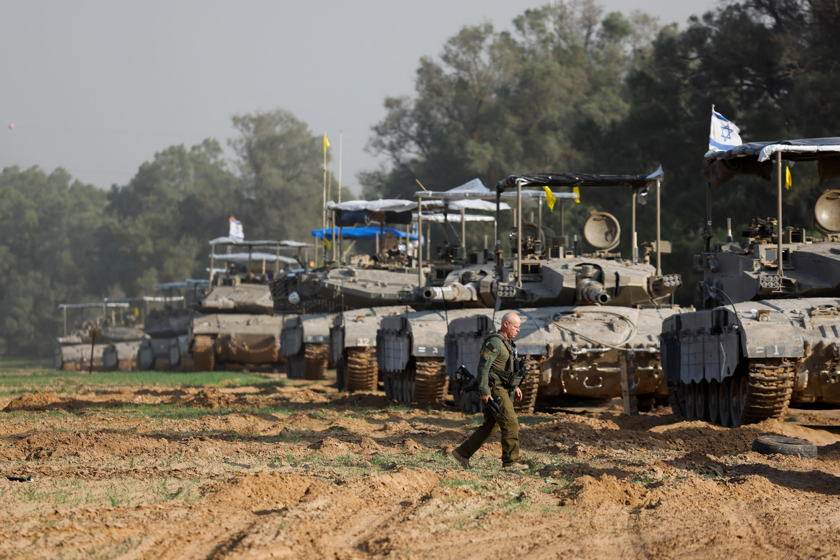 Un soldat israélien marche à côté d'un convoi de chars israéliens, près de la frontière avec la bande de Gaza, le 4 décembre 2023. REUTERS/Amir Cohen