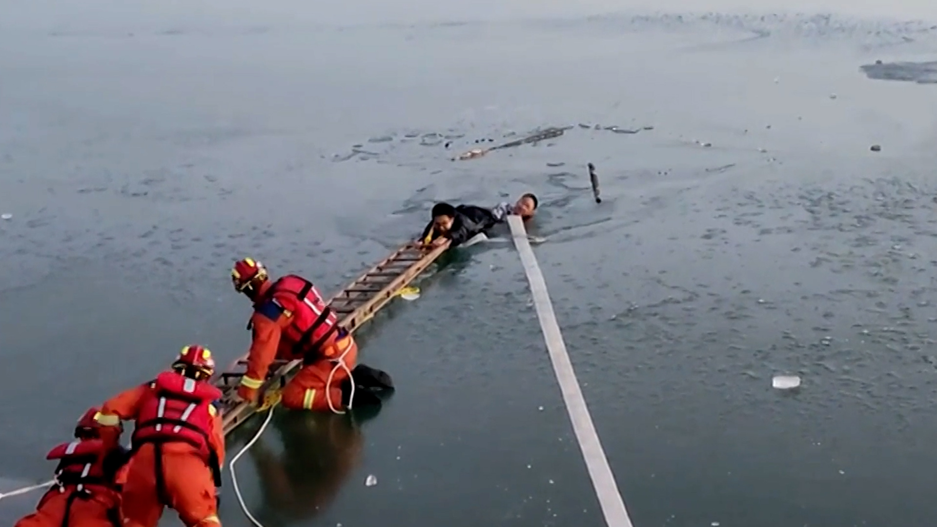 Au moyen d'une échelle à deux sections, les pompiers ont pu atteindre les deux jeunes Chinois frigorifiés, sur la rivière Xiaobai.