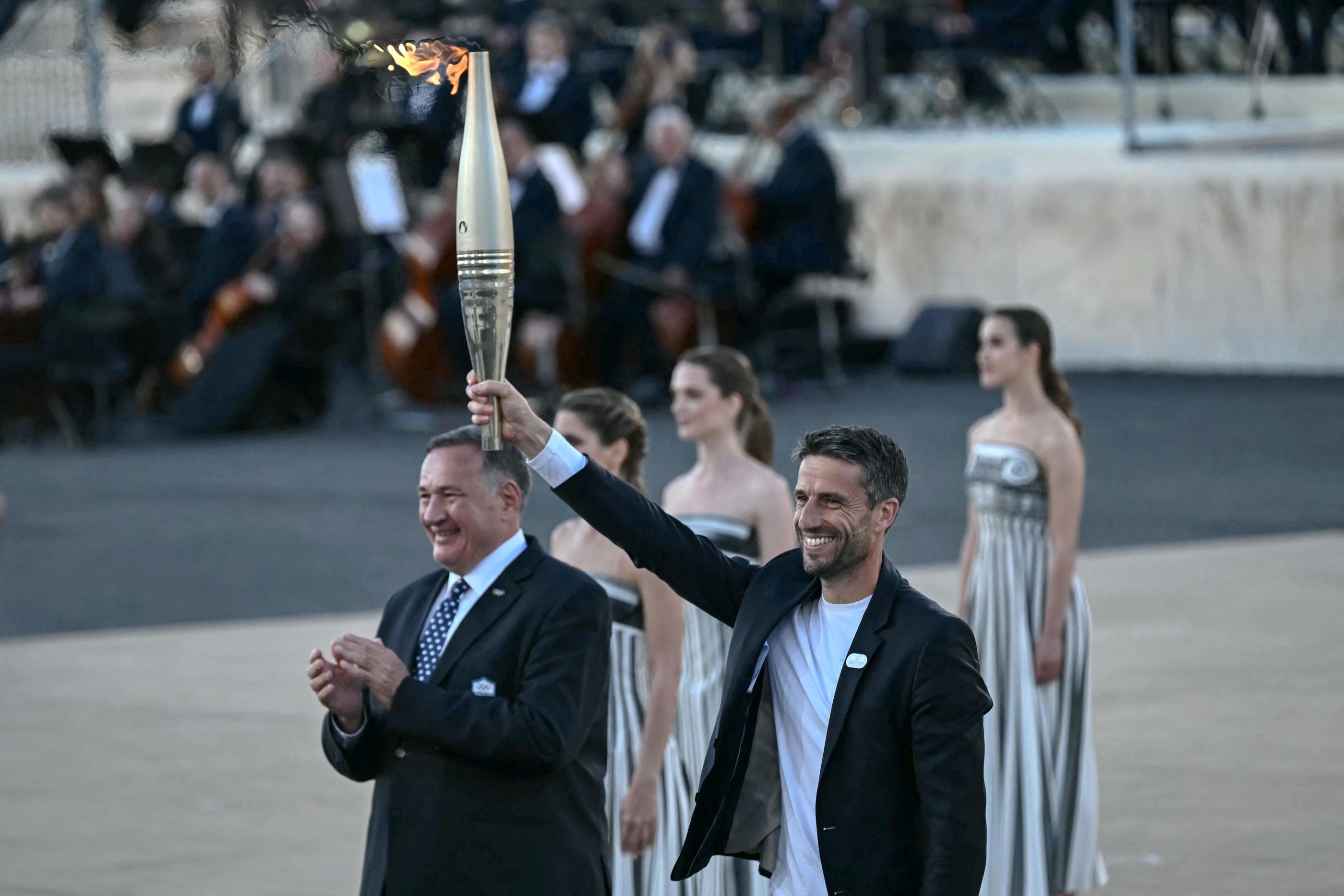 Le président du Cojo Tony Estanguet a reçu la flamme des mains du président du comité olympique grec, Spyros Capralos (à gauche). AFP/Aris Messinis