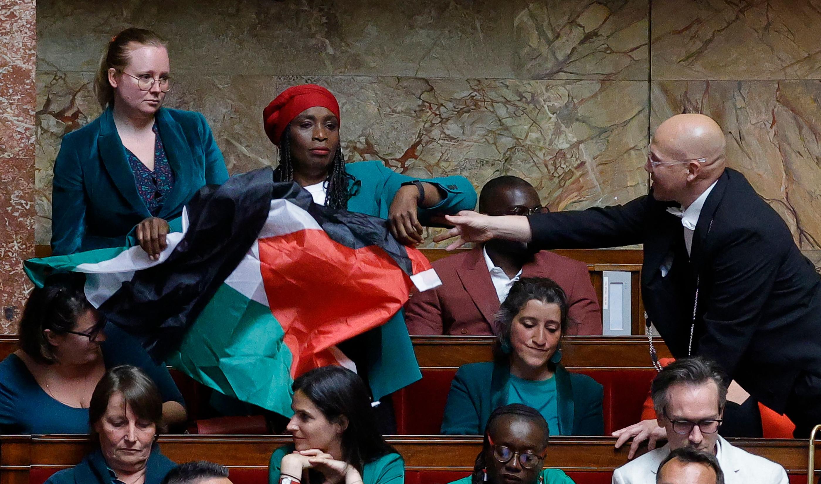 Un huissier tente d'arrêter la députée LFI Rachel Kéké alors qu'elle agite un drapeau palestinien lors d'une séance de questions au gouvernement à l'Assemblée nationale, le 4 juin 2024. AFP/Geoffroy van der Hasselt