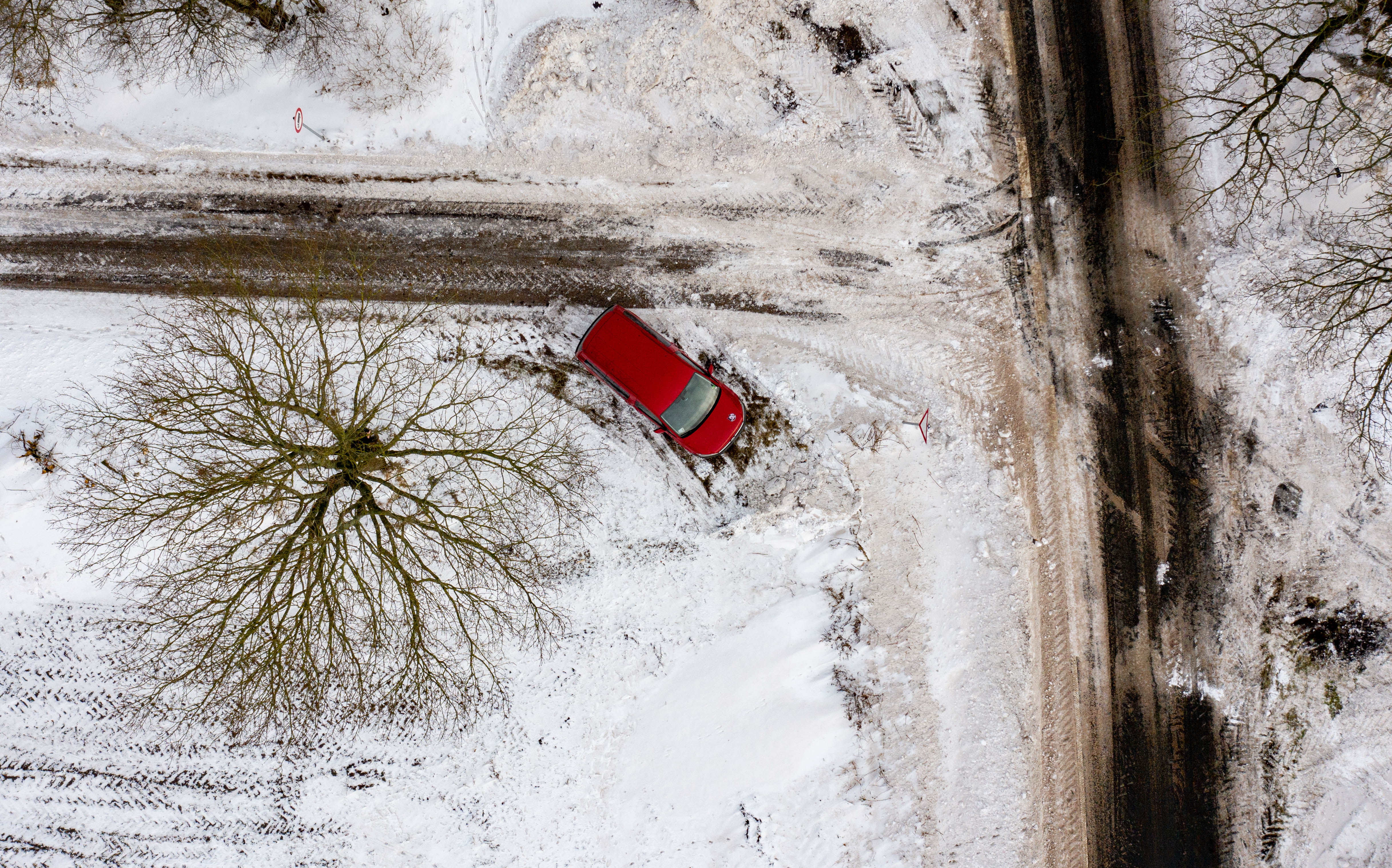 Frau, die schnee von einem auto mit einem besen entfernt