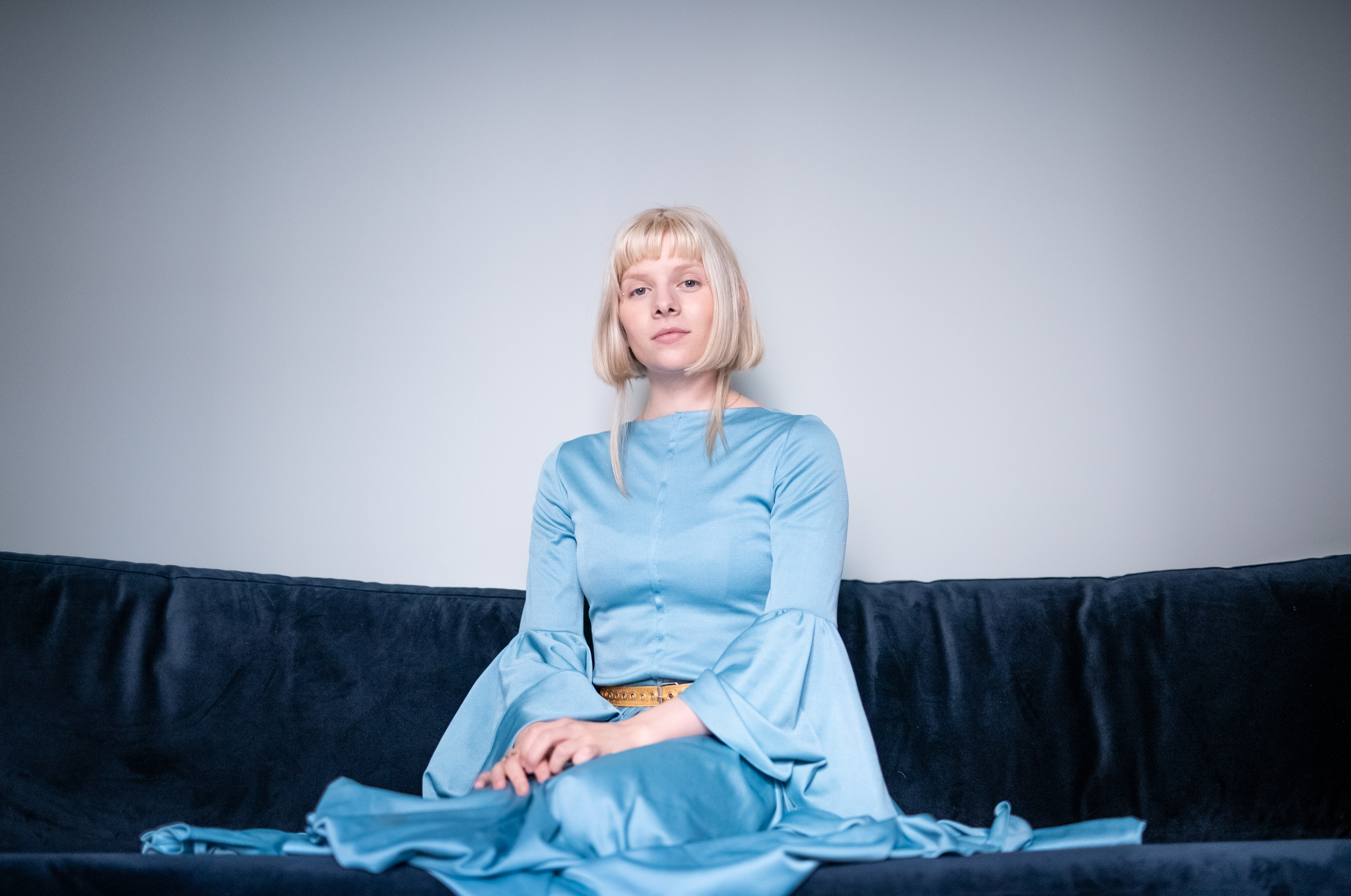 I en blå velursofa, og i blå kjole, sitter Aurora Aksnes.
