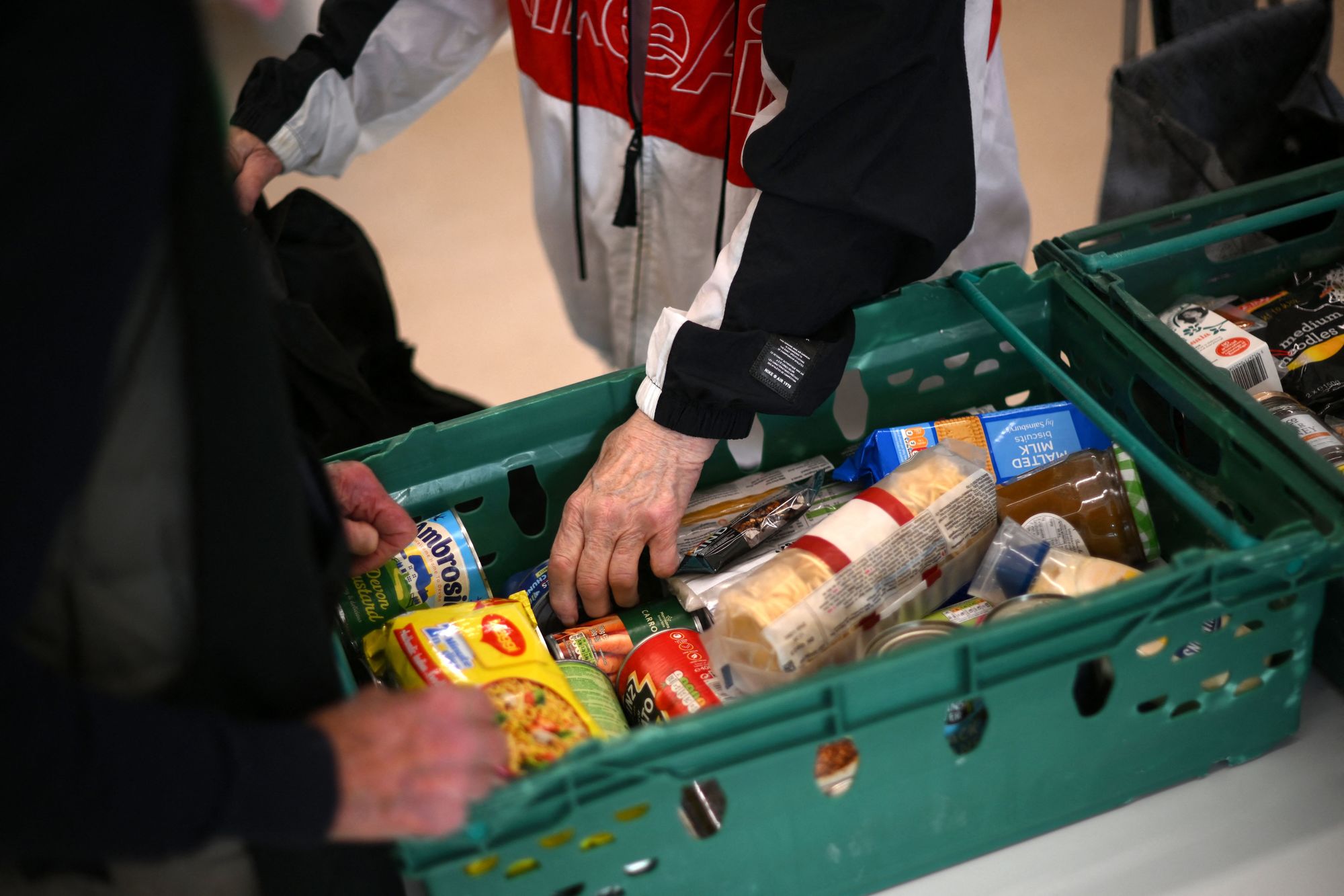 En person ser gjennom maten på et matutdelingssenter i Hackney i London. Mange sliter med å få endene til å møtes i den største levekostnadskrisen på mange tiår.