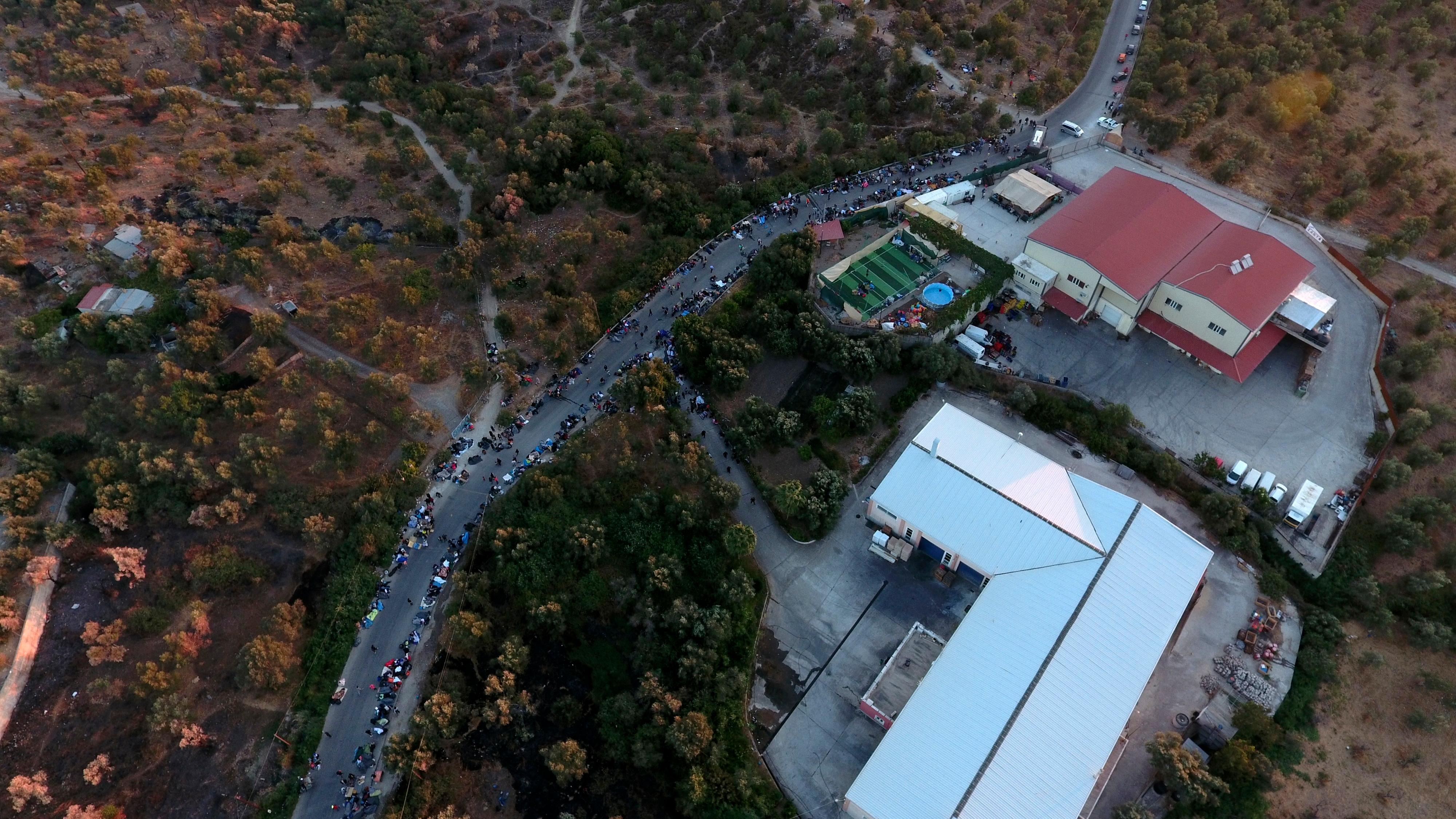 People gather outside the Moria refugee camp during a fire on the northeastern Aegean island of Lesbos, Greece, on Wednesday, Sept. 9, 2020. A fire swept through Greece's largest refugee camp that had been placed under COVID-19 lockdown, leaving more than 12,000 migrants in emergency need of shelter on the island of Lesbos. (AP Photo/Panagiotis Balaskas)