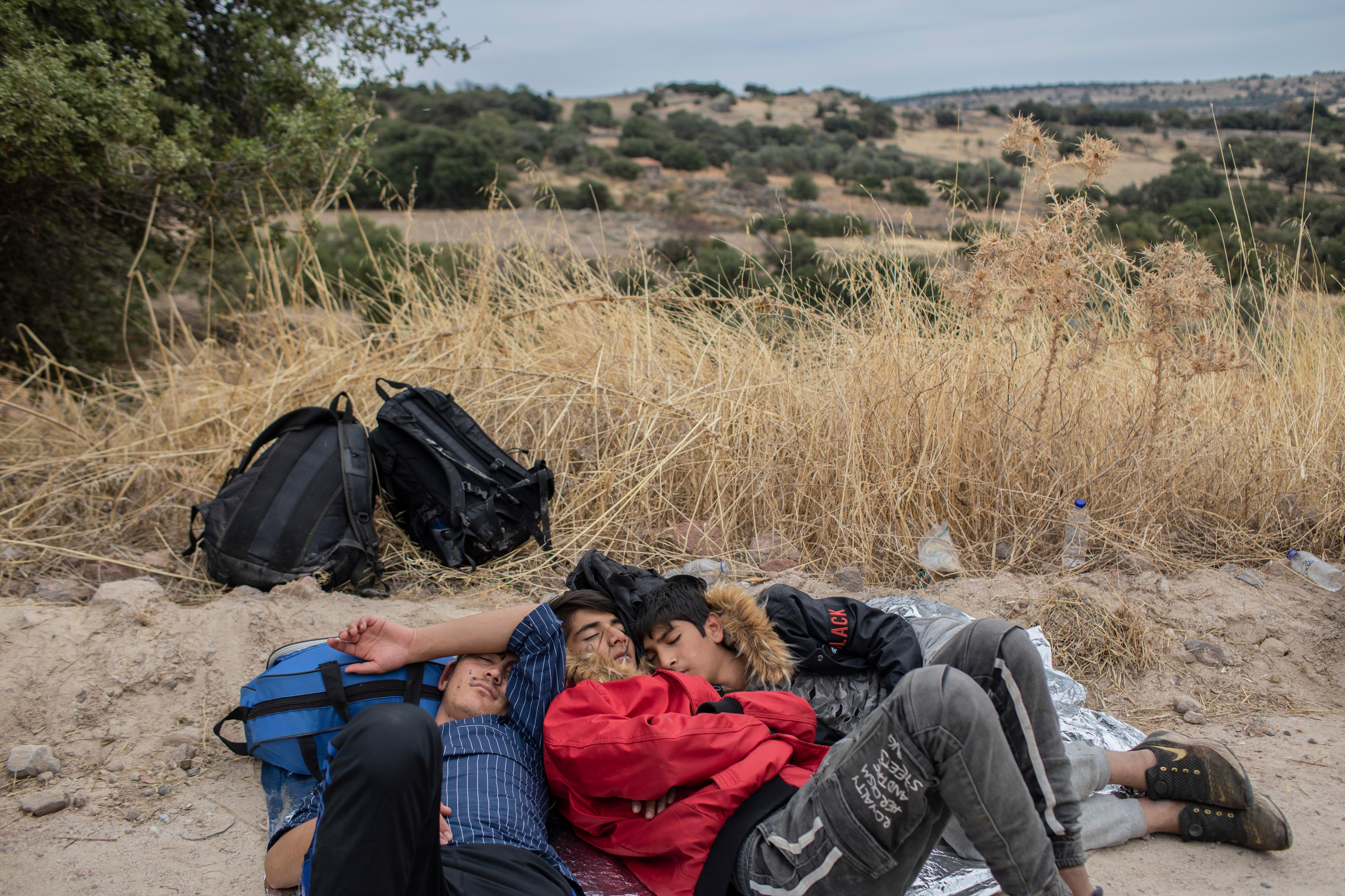 In this Monday, Oct. 7, 2019 photo, exhausted Afghan youths sleep on the ground near the town of Madamados after their arrival with other migrants and refugees on a rubber boat from Turkey, at Lesbos Island, Greece. (AP Photo/Petros Giannakouris)