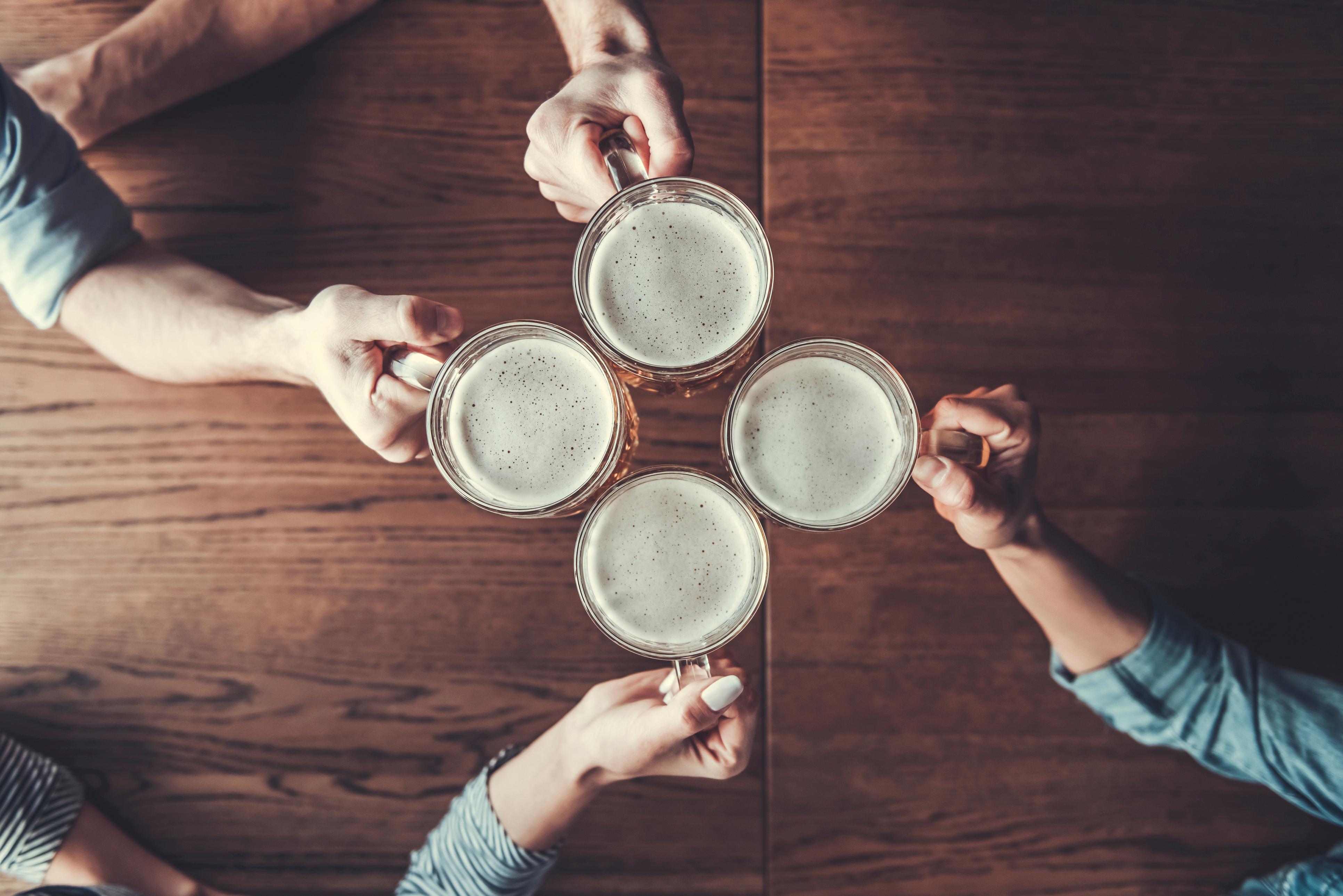 Cheers! Top view of people holding mugs with beer.