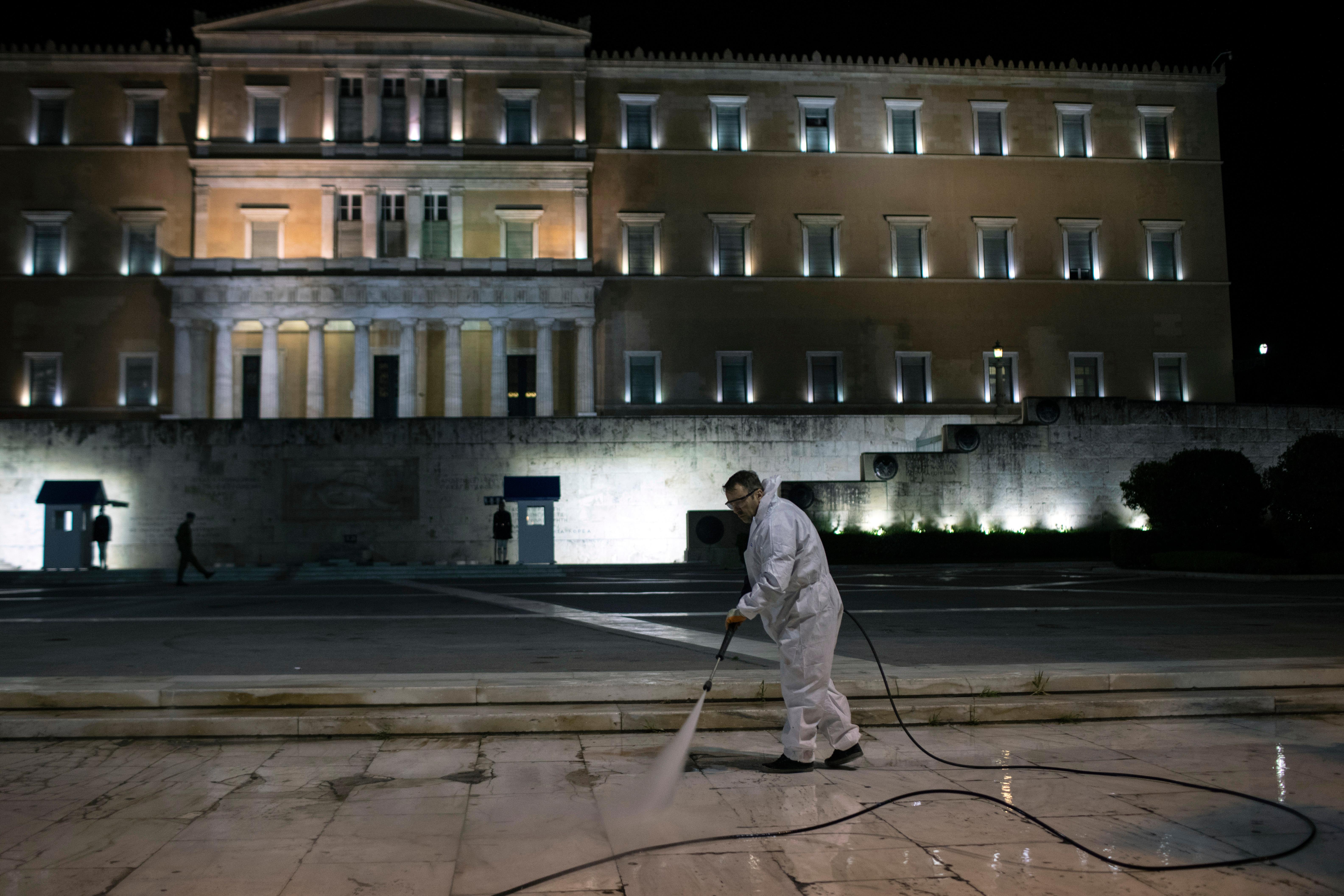 A municipality worker wearing a protective suit sprays disinfectant outside the Greek parliament in Athens during lockdown measures to prevent the spread of the coronavirus, on Friday, May 1, 2020. Greek authorities say the use of face masks will be compulsory on public transport and shops from May 4, when the country starts to ease its lockdown restrictions. (AP Photo/Petros Giannakouris)