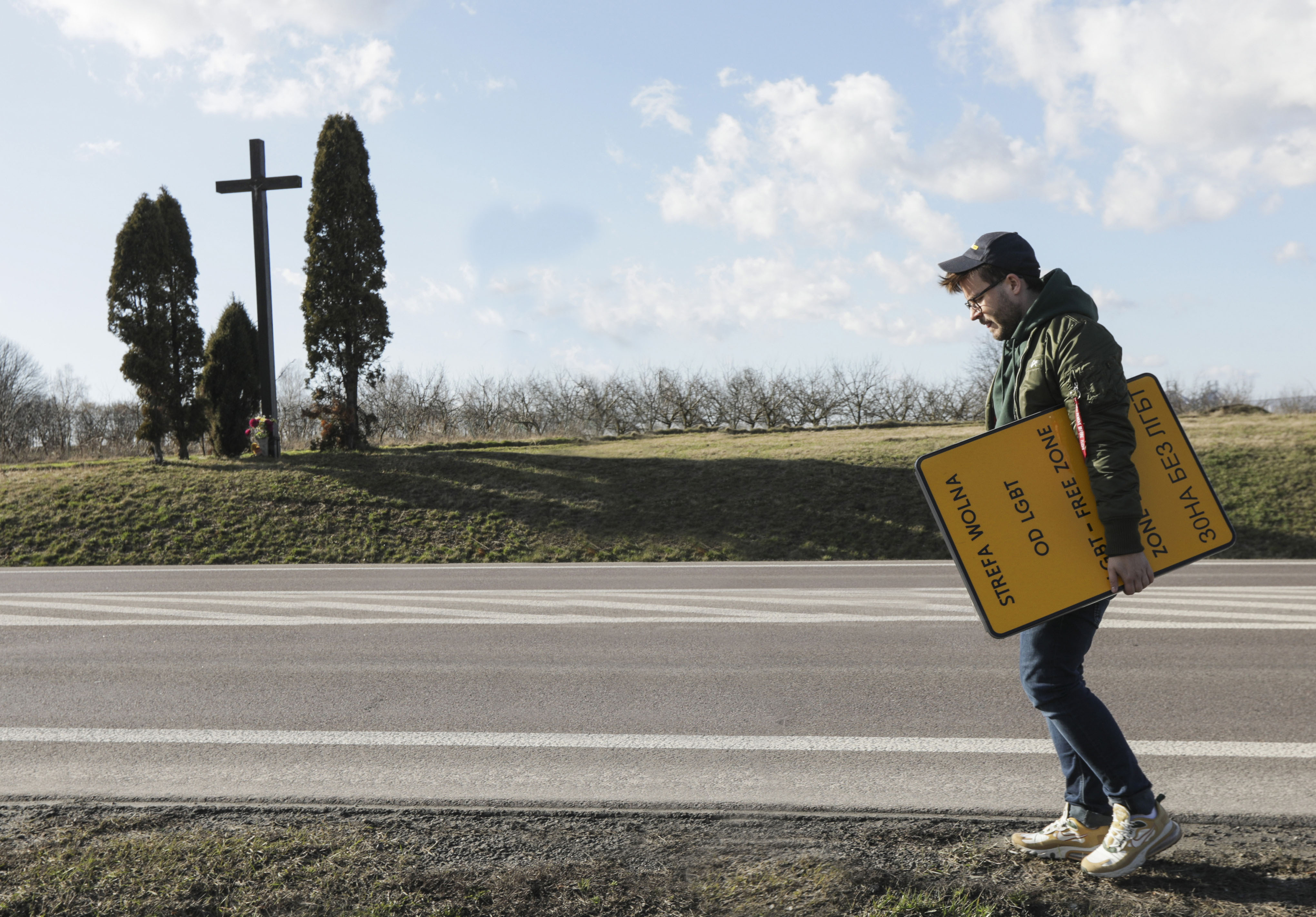 Bart Staszewski, an LGBT activist, walks with a sign he uses to protest anti-LGBT resolutions, in Wilko?az, Poland on March 11, 2020. Staszewski has carried out a protest in some 40 Polish towns that have passed resolutions declaring themselves opposed to "LGBT ideology." Staszewski's protest involves photographing a sign he made with the words "LGBT-Free Zones" alongside the town's official signage. As international pressure mounts on Poland over its treatment of LGBT people, the prime minister has accused Staszewski of falsifying Poland's image. (AP Photo/Monika Bryk)