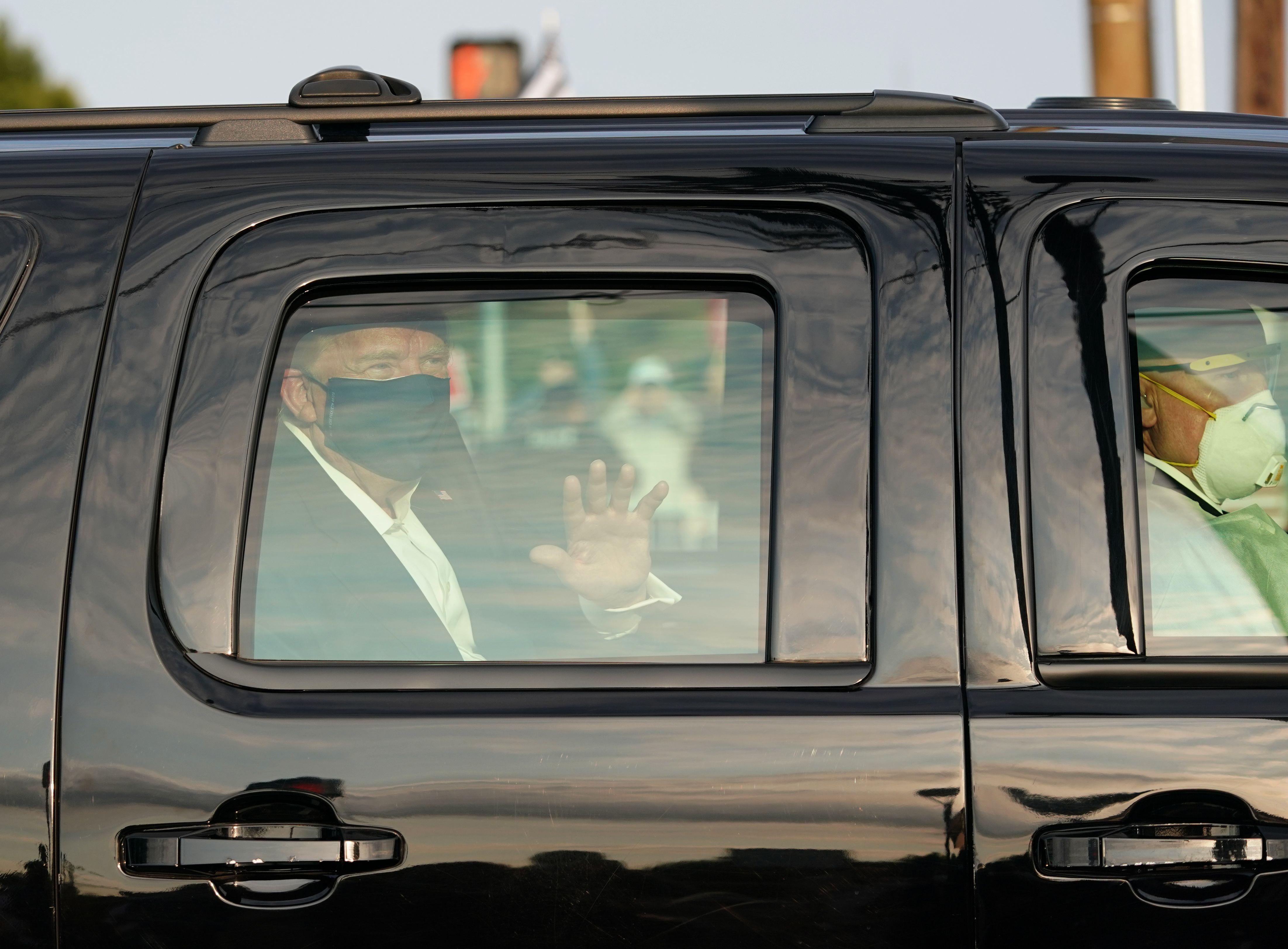 A car with US President Trump drives past supporters in a motorcade outside of Walter Reed Medical Center in Bethesda, Maryland on October 4, 2020. (Photo by ALEX EDELMAN / AFP)