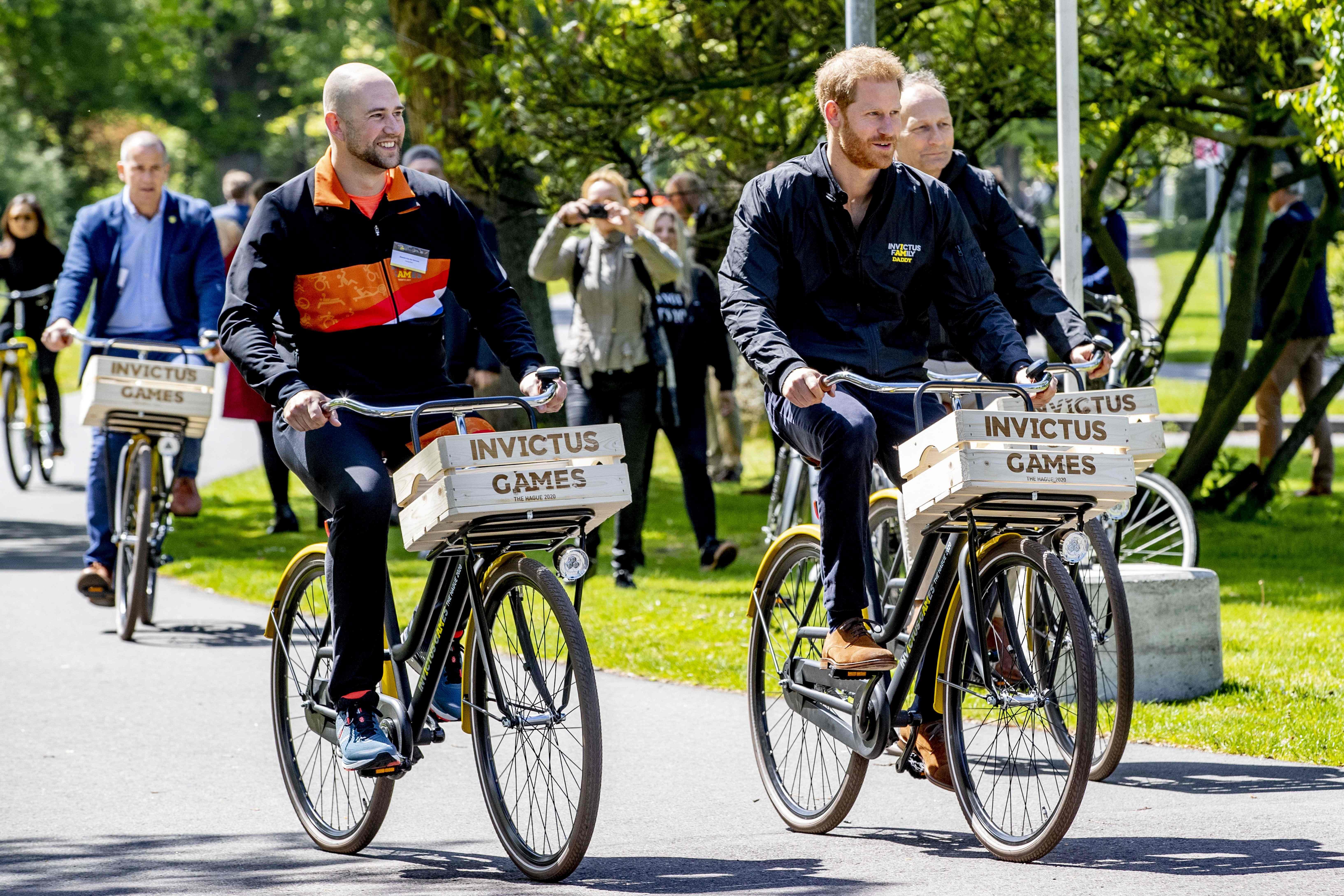 Former Dutch serviceman and athlete Dennis Van Der Stroom (L) and Prince Harry (R) ride a bike during the presentation of the Invictus Games The Hague 2020, in The Hague, Netherlands, on May 9, 2019. - The fifth Invictus Games The Hague 2020, an international sporting event for wounded, injured and sick servicepersonnel, will be held in the Zuiderpark in 2020. (Photo by patrick van katwijk / ANP / AFP) / Netherlands OUT