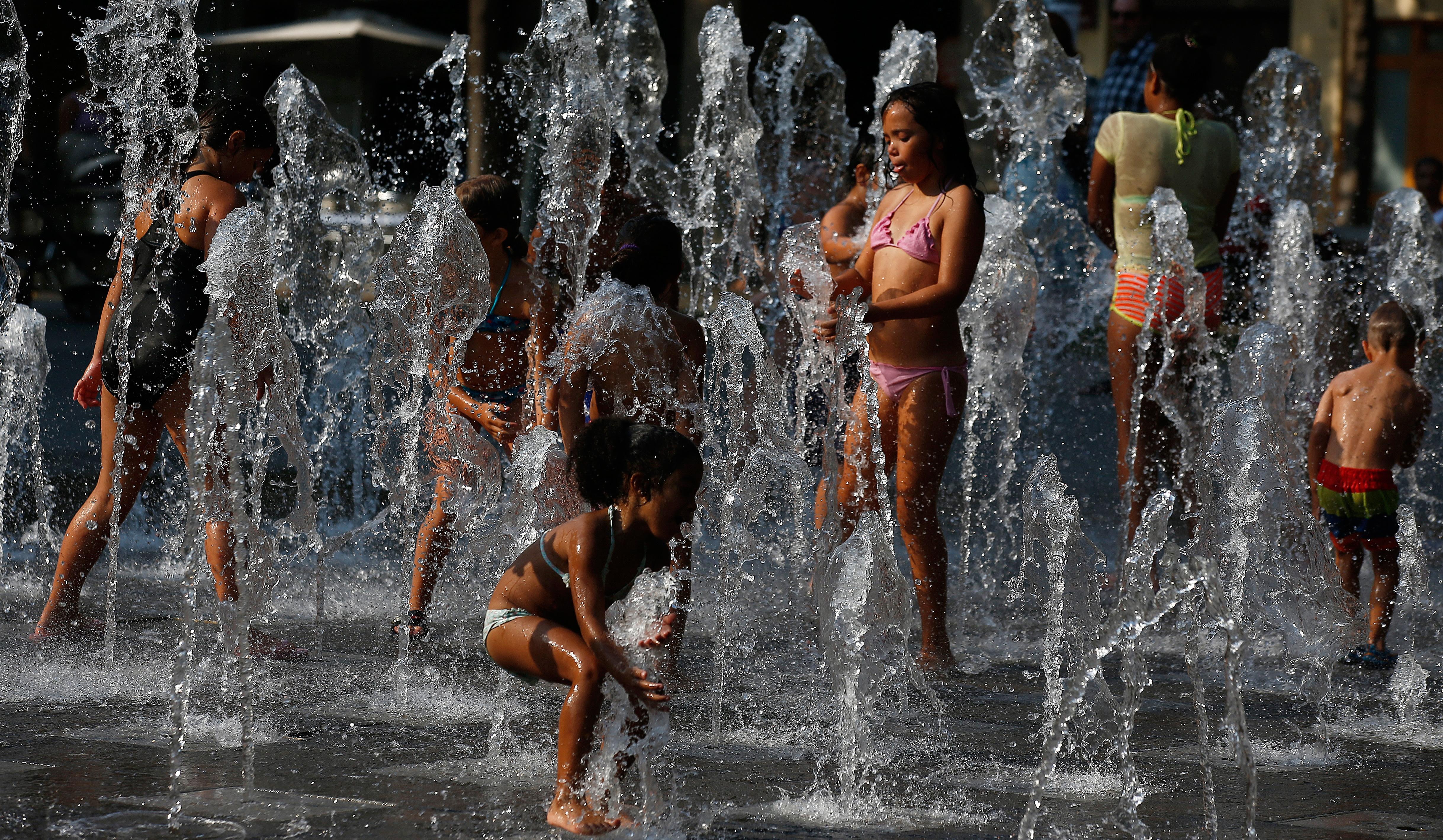Bildet viser folk som kjøler seg ned i fontener i i Barcelona i Spania.