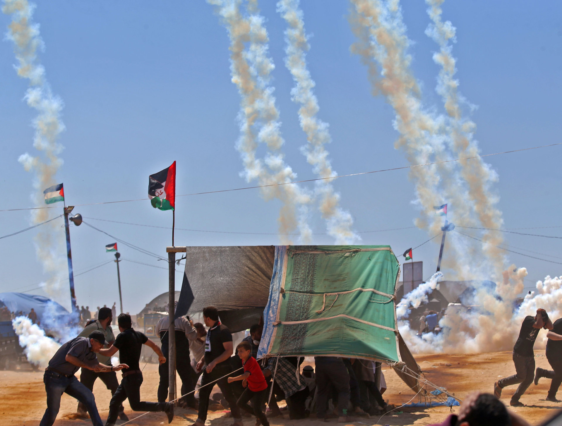 Tåregass: Palestinere løper under tåregass som israelske styrker skyter over grensa mellom Israel og Gazastripen. FOTO: NTB SCANPIX