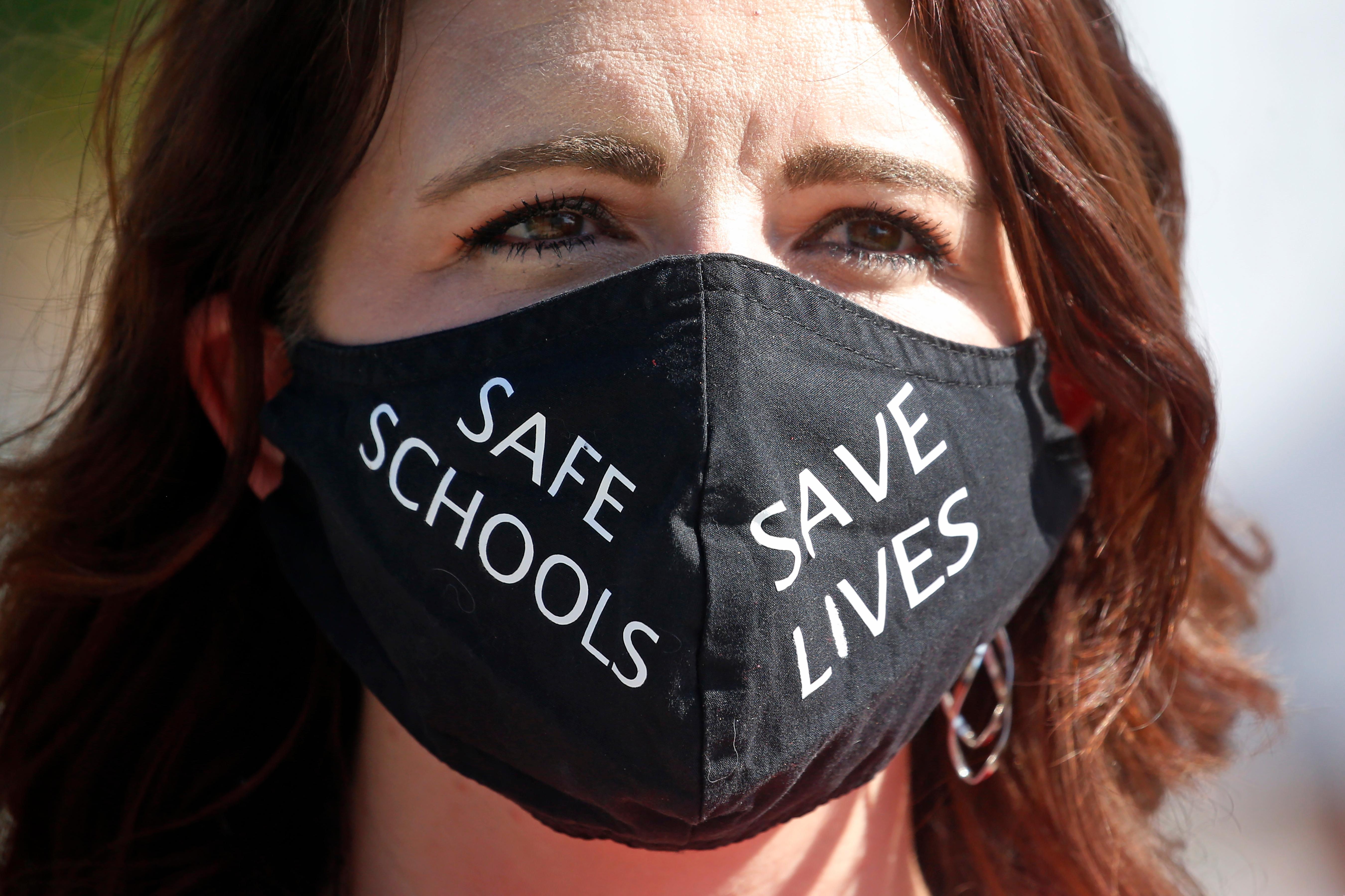 Utah school teacher Emily Johnson protests with other teachers at the Utah State Capitol, Friday, Aug. 7, 2020, in Salt Lake City. The Utah Board of Education has rejected multiple proposals requiring stricter precautions against the coronavirus as schools reopen across the state. The board voted 9-5 Thursday against a series of mandates, including one that would limit the number of students in a classroom if community spread spikes above the 5% reopening threshold set by the World Health Organization, the Deseret News reported. (AP Photo/Rick Bowmer)