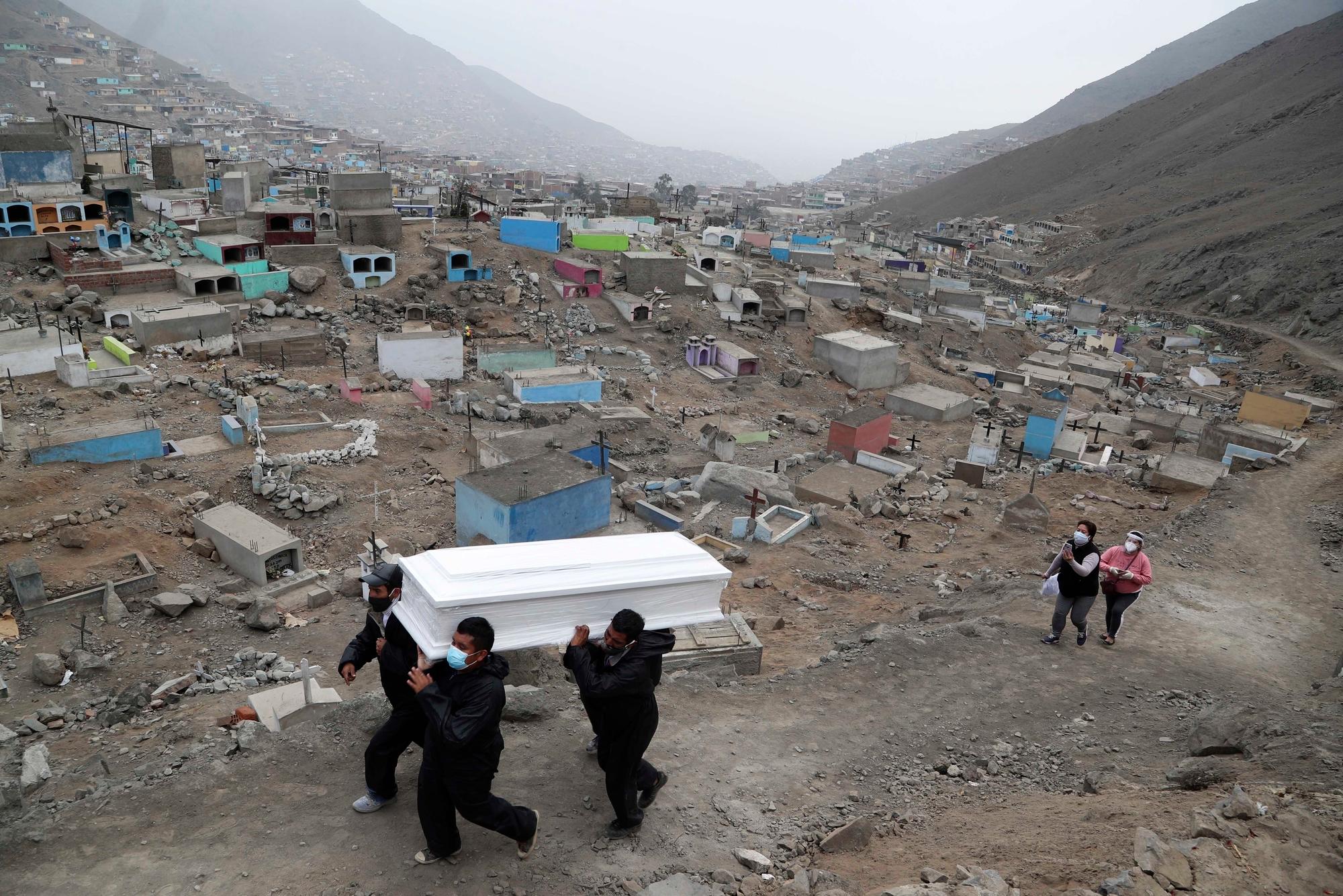 Cemetery workers carry the coffin that contains the remains of Wilson Gil, who family members say died of COVID-19 related complications, to a burial site at the Martires 19 de Julio cemetery on the outskirts of Lima, Peru, Wednesday, Aug. 26, 2020. The South American country has the highest number of new coronavirus infections in Latin America after Brazil. (AP Photo/Martin Mejia)