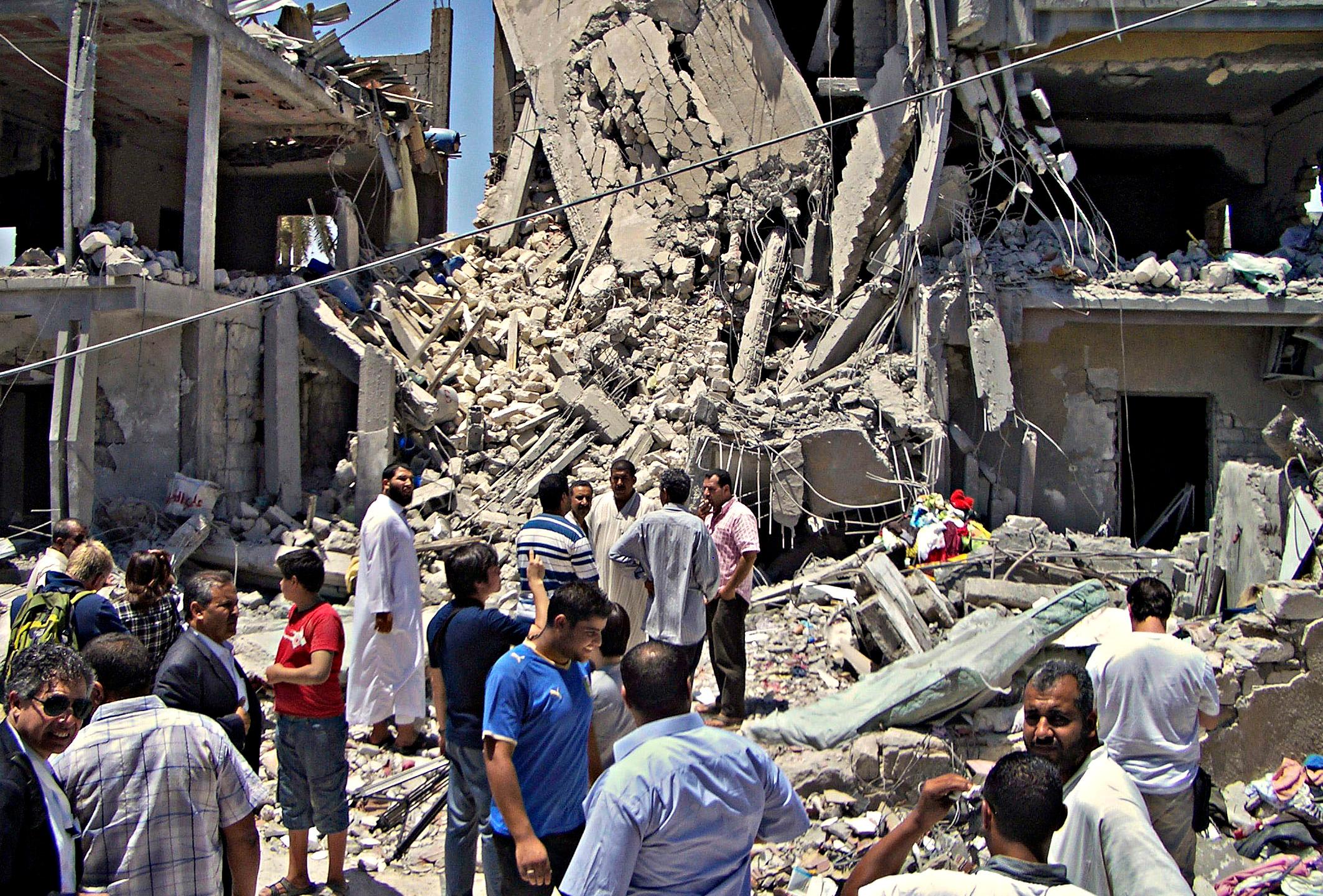 FILE - In a June 19, 2011, file photo made on a government-organized tour, members of the media and others examine the remains of a damaged residential building in Tripoli, Libya. Human Rights Watch is calling on NATO to provide compensation for Libyans who lost loved ones or had property damaged in airstrikes during the bombing campaign that helped rebels oust former leader Moammar Gadhafi.  (AP Photo/Adam Schreck, File)