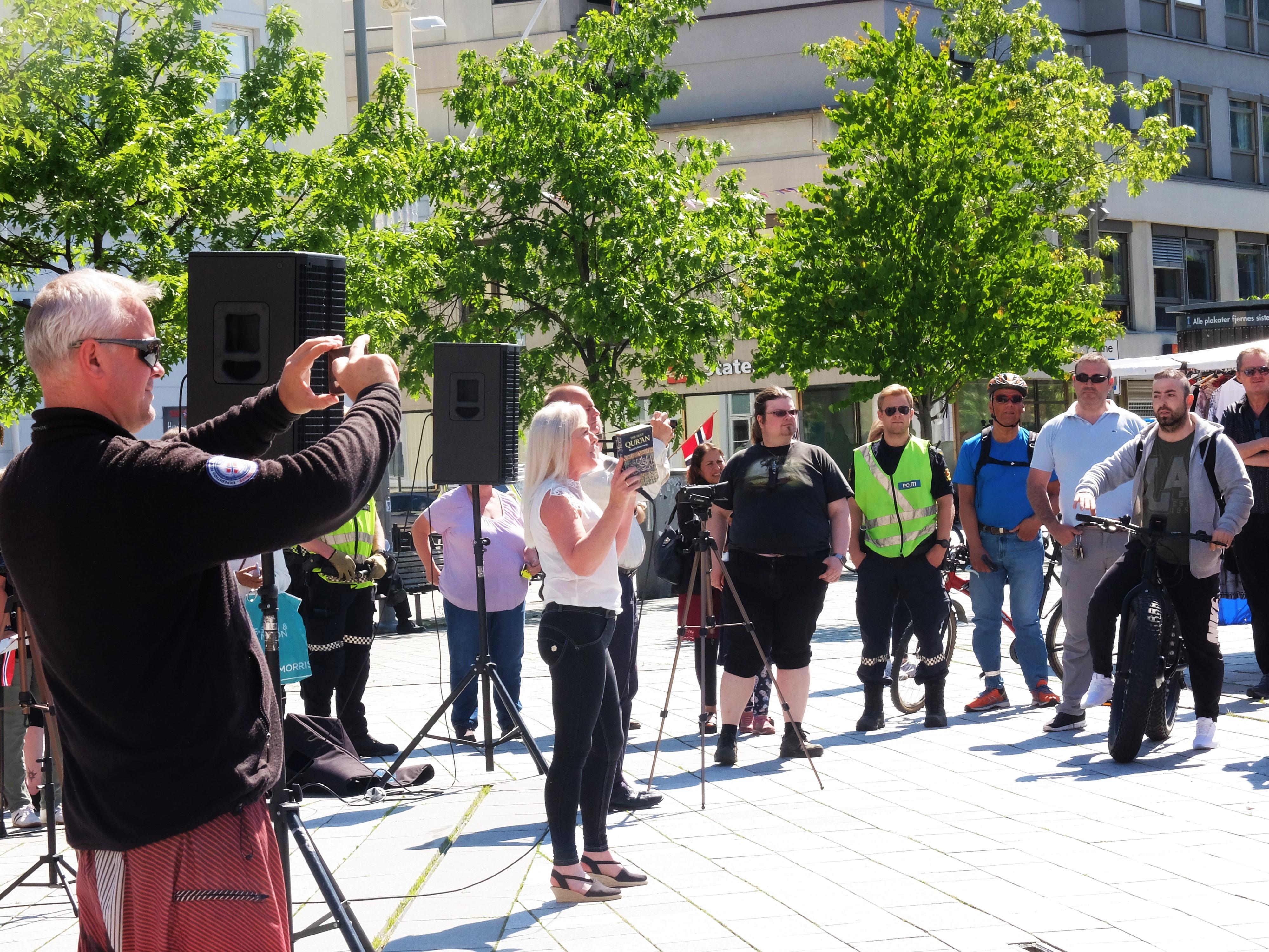 Anna Bråten og stadig mer opphissede tilhørere filmes og fotograferes av andre representanter for SIAN, mens hun holder opp en utgave av koranen og avslutter med å kaste den i bakken. FORO: KATRINE STRØM