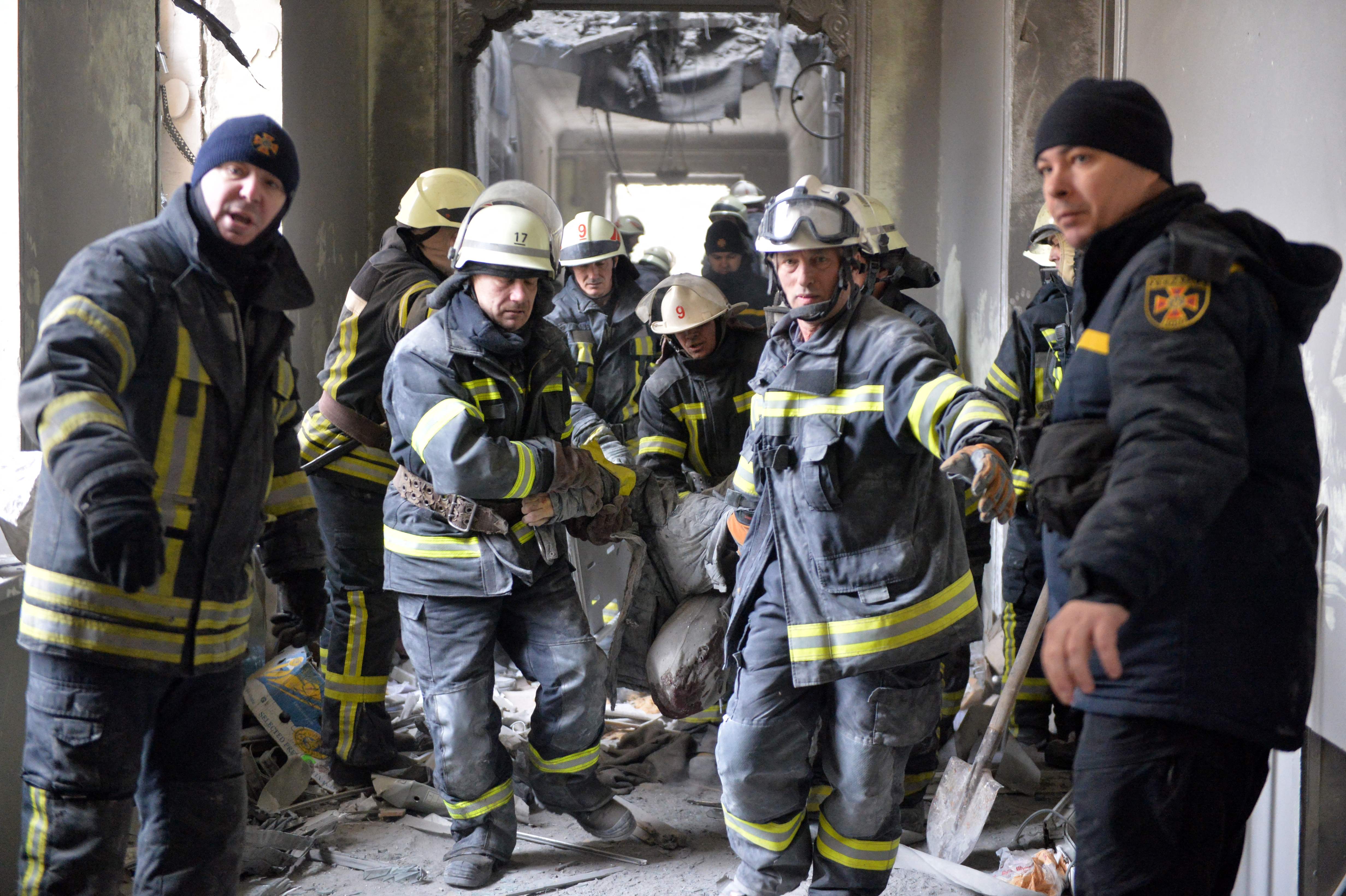 Hjelpemannskaper bærer en person ut av et bygg i Kharkiv som ble rammet i et russisk angrep mot byen tirsdag.