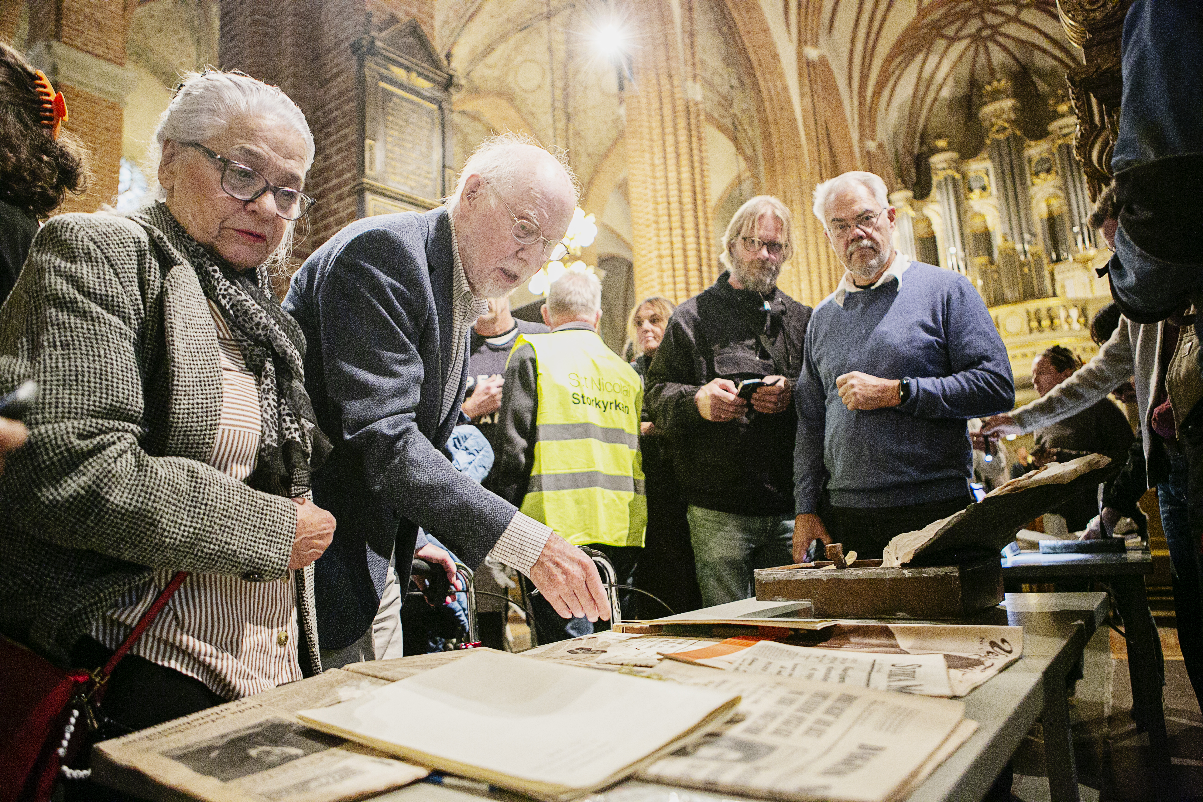 Anne-Maria Axelsdotter och Per Hansson, medlemmar i kyrkorådet i Stockholms domkyrkoförsamling, betraktar innehållet i en av de tidskapslar som öppnades i Storkyrkan i torsdags.