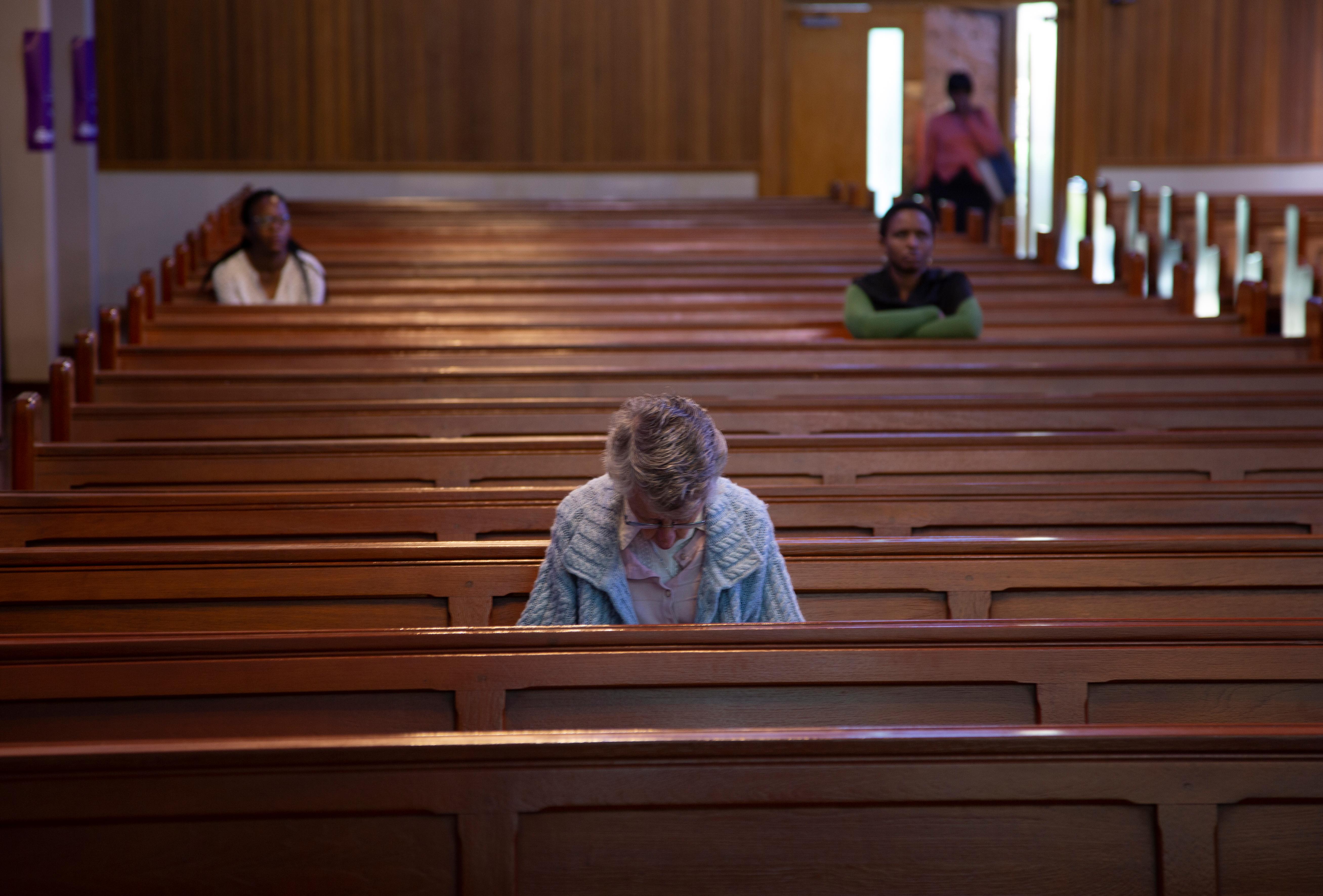 Few worshippers pray at the Rosebank Catholic Church In Johannesburg, South Africa, Thursday, March 19, 2020. South Africa imposed restrictions and banned gathering of 100 and more in a bid to prevent the spread of the coronavirus. For some people the COVID-19 coronavirus causes mild or moderate symptoms, but for some it causes severe illness. (AP Photo/Denis Farrell)