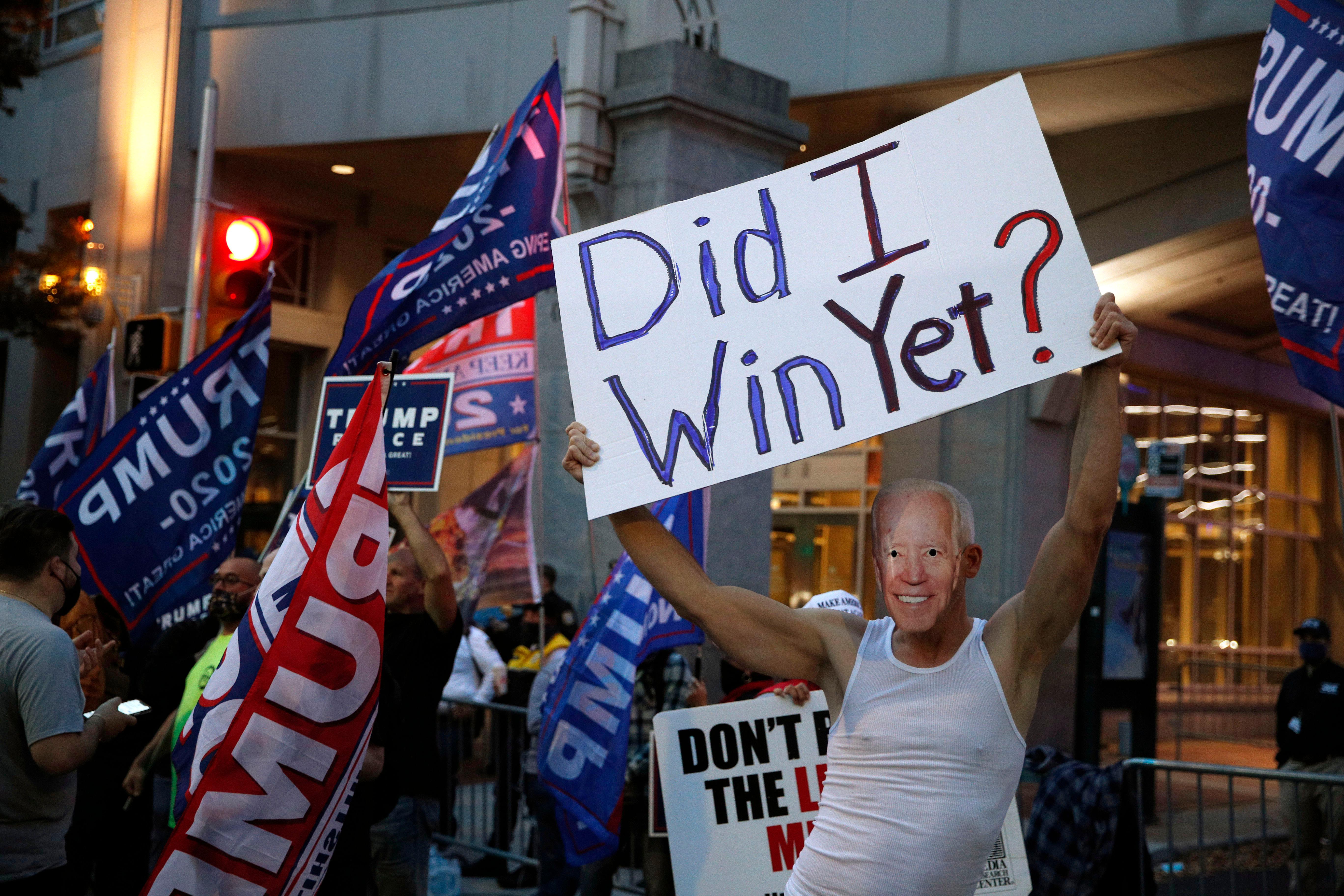 A supporter of President Donald Trump wears a mask made from a photograph of Vice President Joe Biden outside the Pennsylvania Convention Center where votes are being counted, Thursday, Nov. 5, 2020, in Philadelphia, following Tuesday's election. (AP Photo/Rebecca Blackwell)