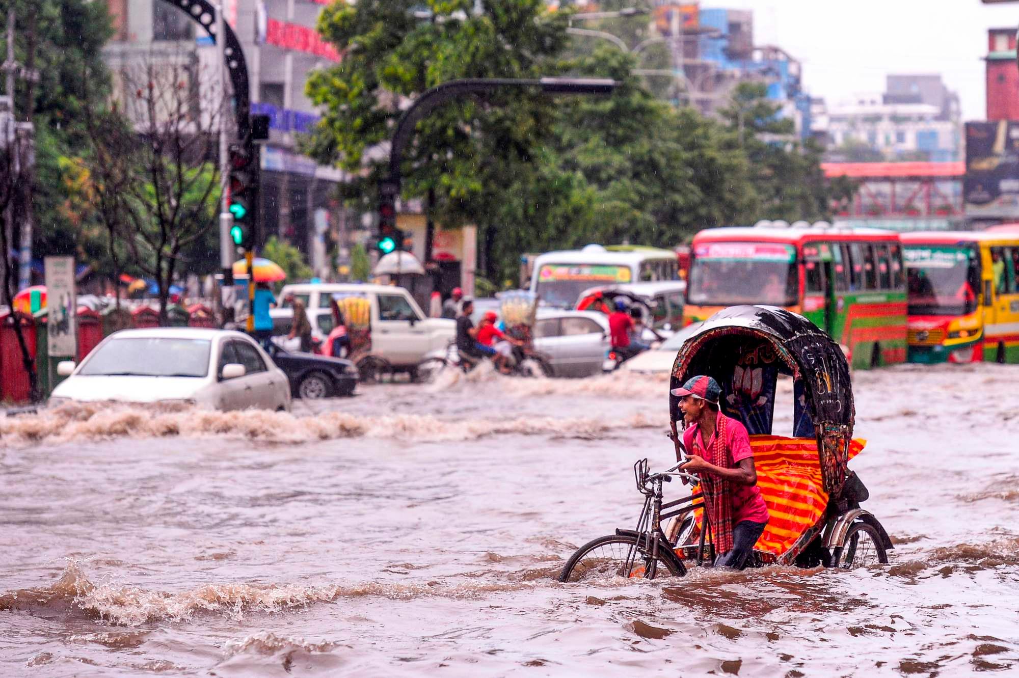 A Bangladeshi rickshaw puller makes his way through heavy rainfall at a water-logged street during the monsoon season in Dhaka on July 12, 2019. (Photo by MUNIR UZ ZAMAN / AFP)