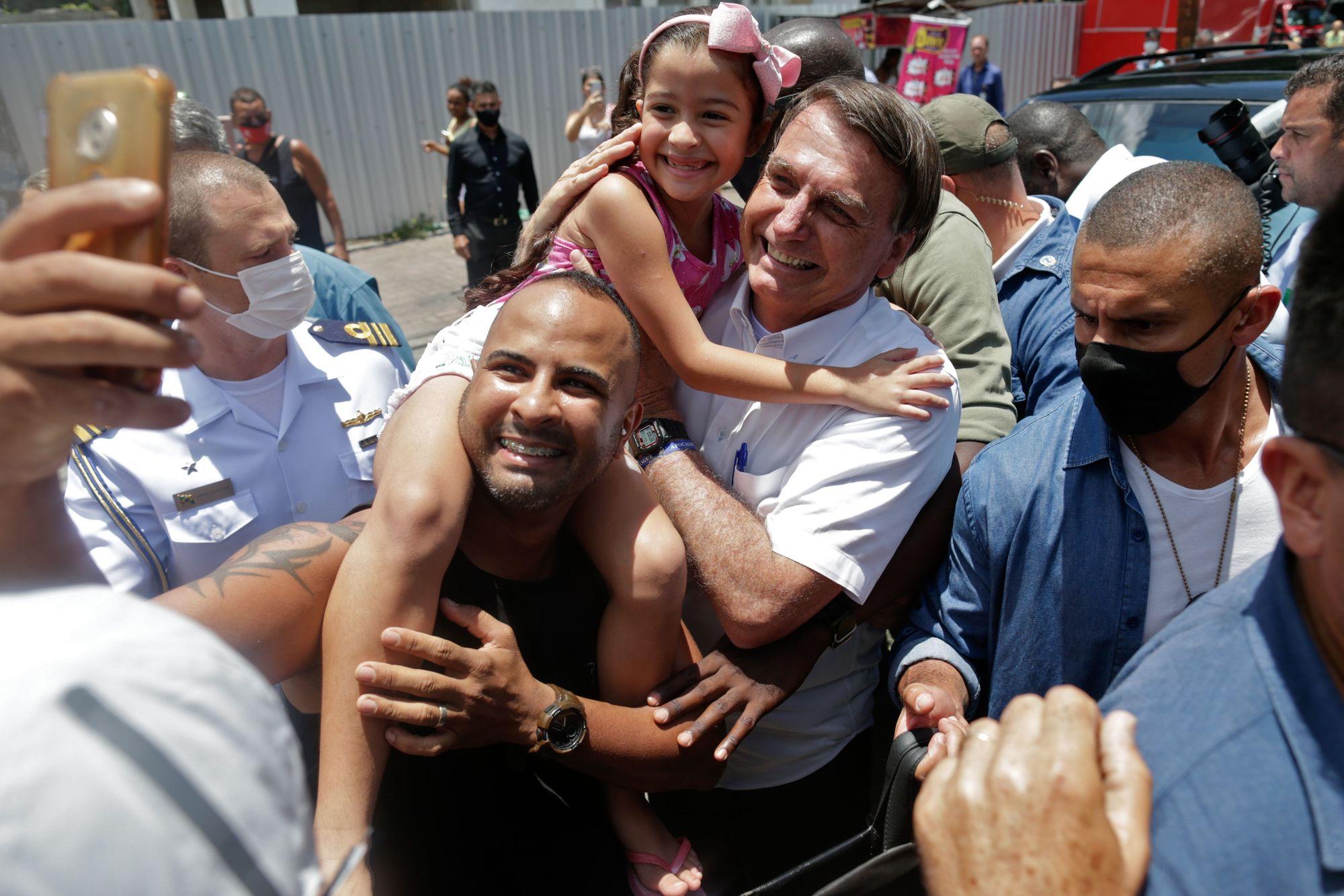 Brazilian President Jair Bolsonaro (C) poses for a selfie with supporters after voting during the second round of municipal elections at the Rosa da Fonseca Municipal School, in the Military Village, Rio de Janeiro, Brazil, on November 29, 2020. - Brazilians go to the polls Sunday to chose mayors in 57 cities, including Sao Paulo and Rio de Janeiro, the most rich and populated, in a runoff marked by the economic crisis and an upsurge of the new coronavirus. (Photo by Andre Coelho / AFP)