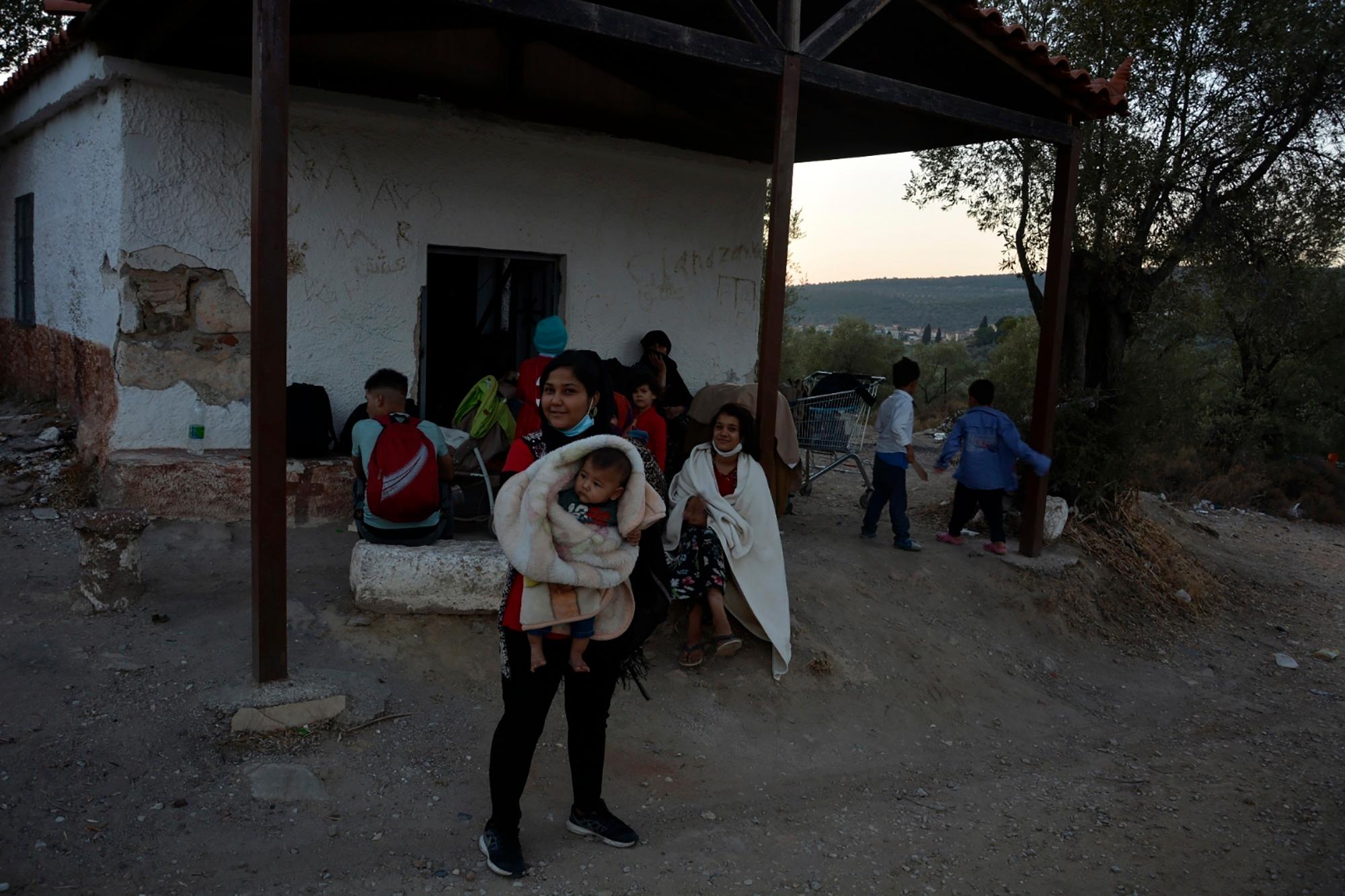 Migrants gather outside an abandoned building during a fire in the Moria refugee camp on the northeastern Aegean island of Lesbos, Greece, on Wednesday, Sept. 9, 2020. Thousands of migrants fled a camp under COVID-19 lockdown after multiple fires gutted much of the site on the Greek island of Lesbos, authorities said early Wednesday. (AP Photo/Panagiotis Balaskas)