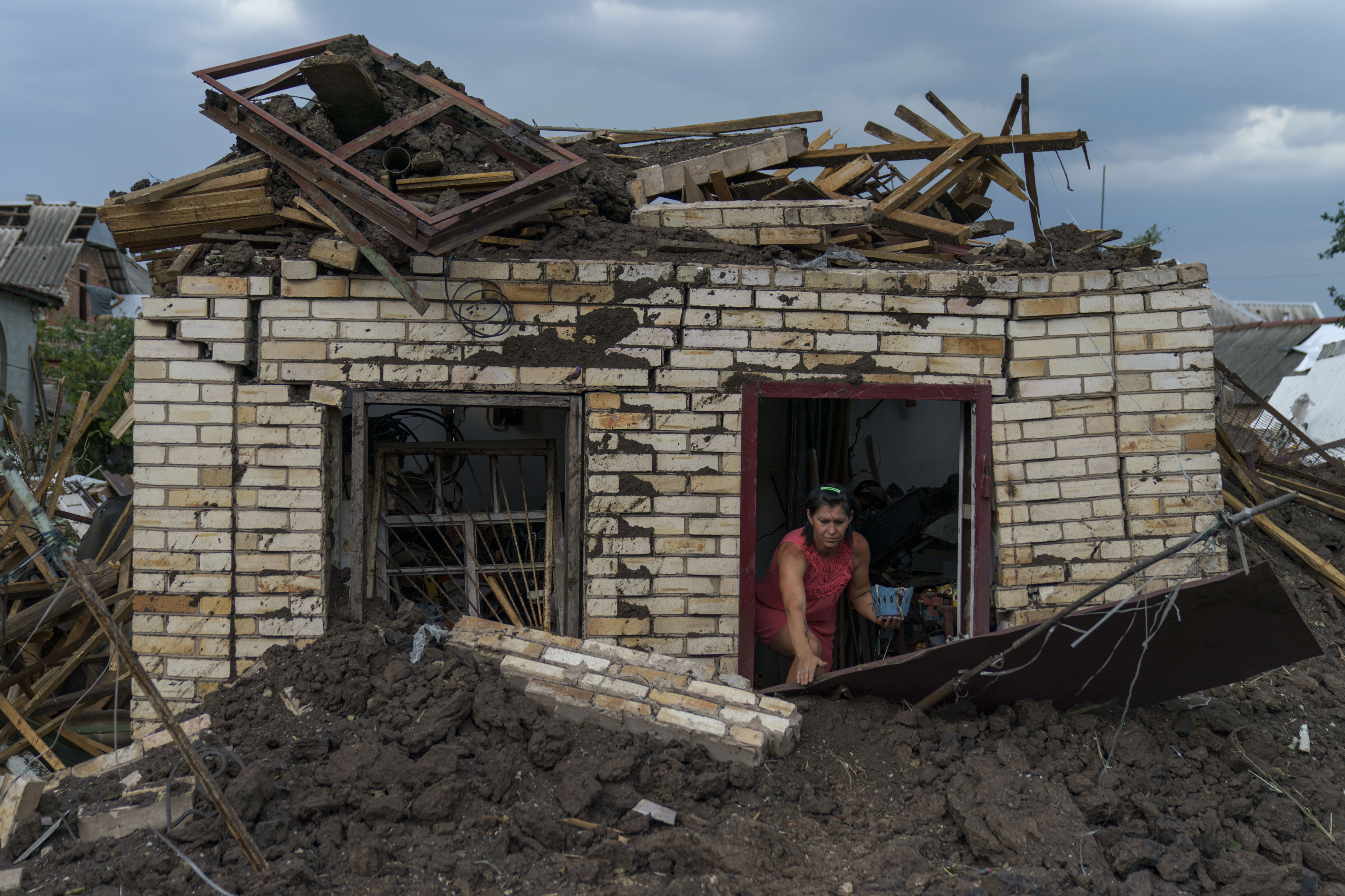 Olga Rudneva hjelper en eldre nabo med å hente gjenstander ut av huset, som ble ødelagt i et russisk angrep mot i Donetsk-regionen tidligere i måneden. Foto: AP / NTB