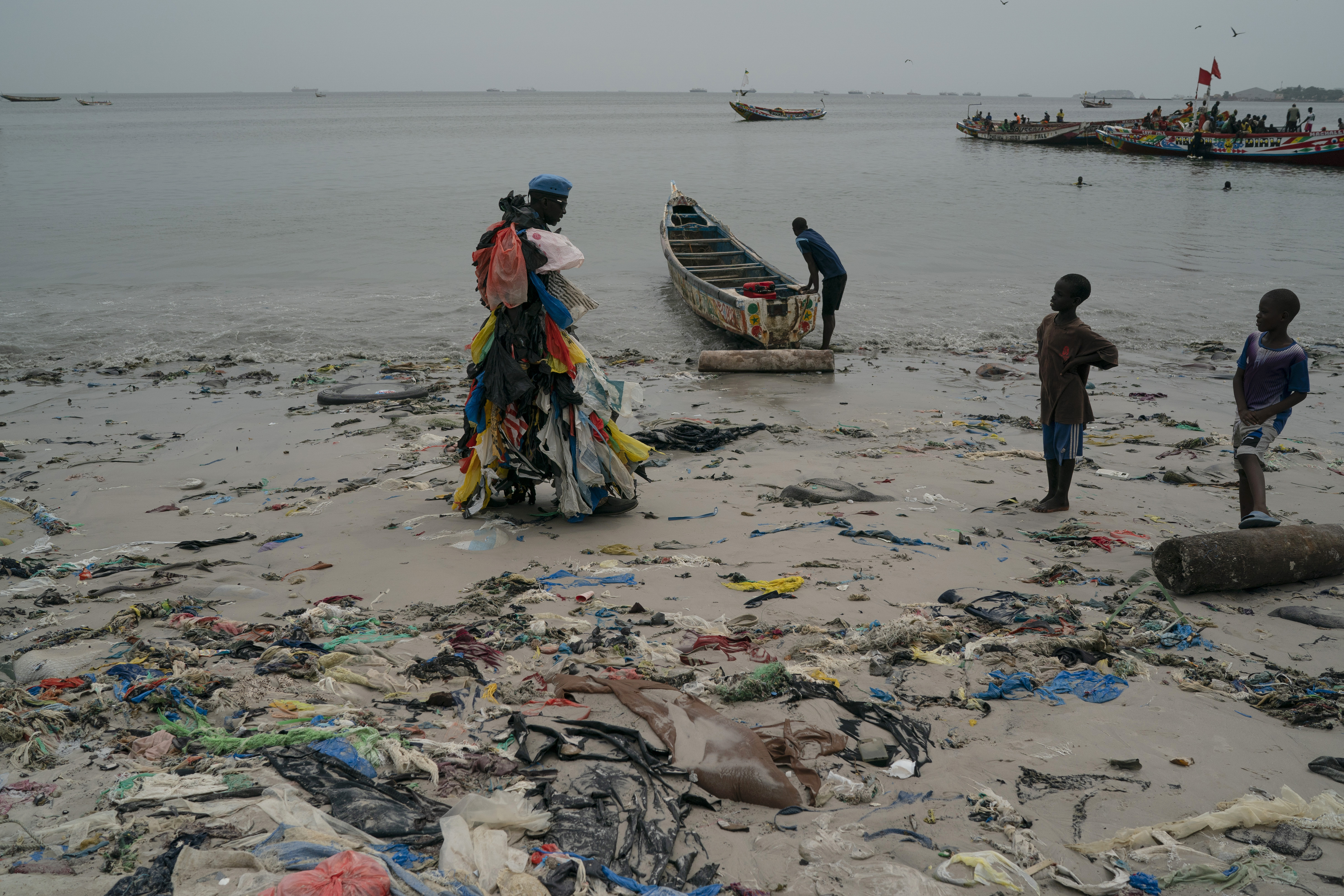 Miljøaktivist Modou Fall fra Senegal, også kalt plastmannen, prøver å spre budskapet om at vi må stanse plastforurensningen. Her forteller han barn på stranda om hva man kan gjøre for å stanse forurensningen. Foto: Leo Correa / AP / NTB