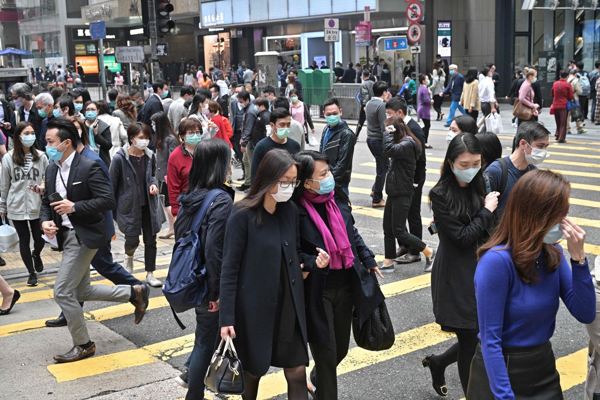 Pedestrians wear face masks, as a precautionary measure against the COVID-19 coronavirus, in Hong Kong on March 12, 2020. (Photo by Anthony WALLACE / AFP)