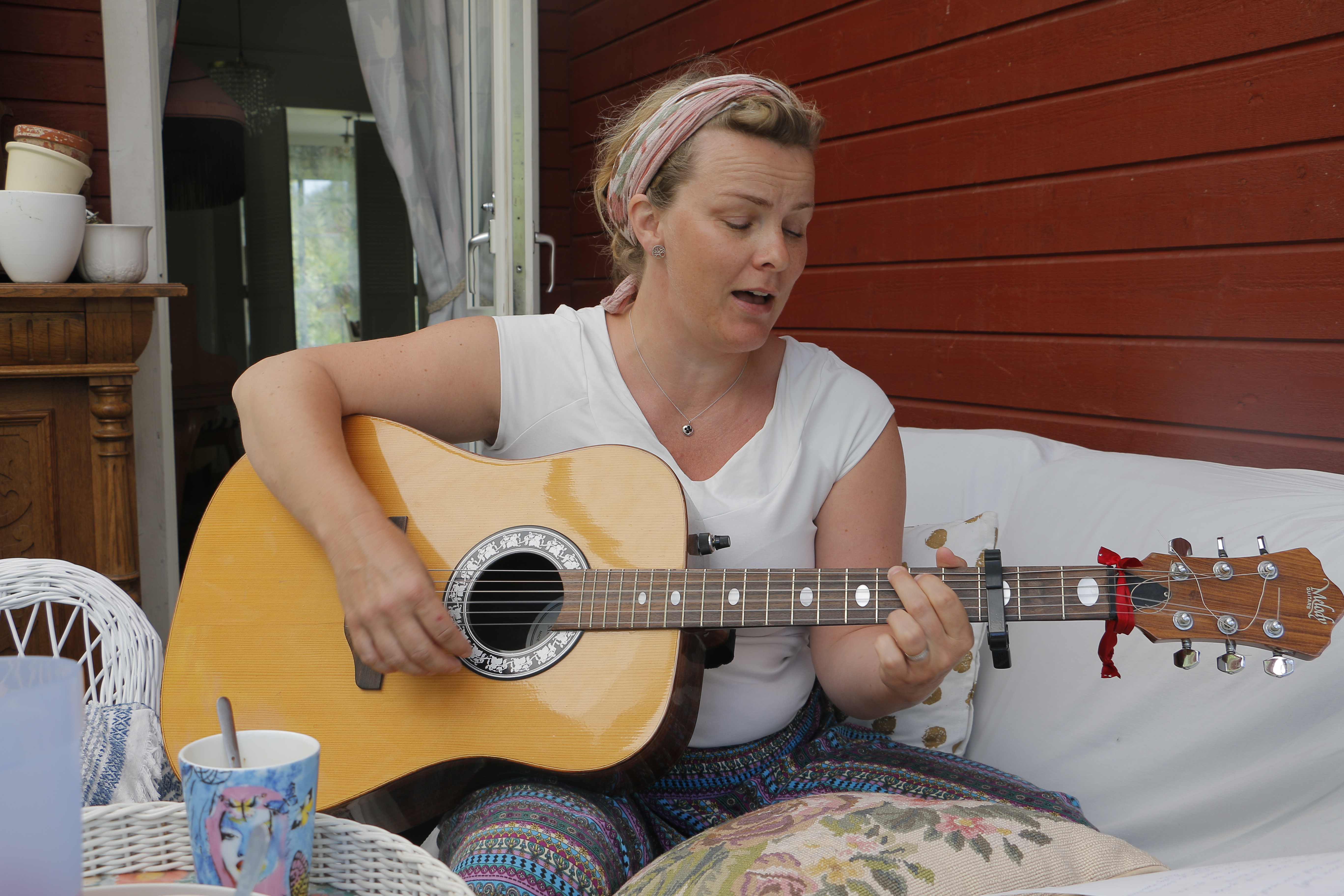 Sara Frigell spelar gitarr i en soffa.