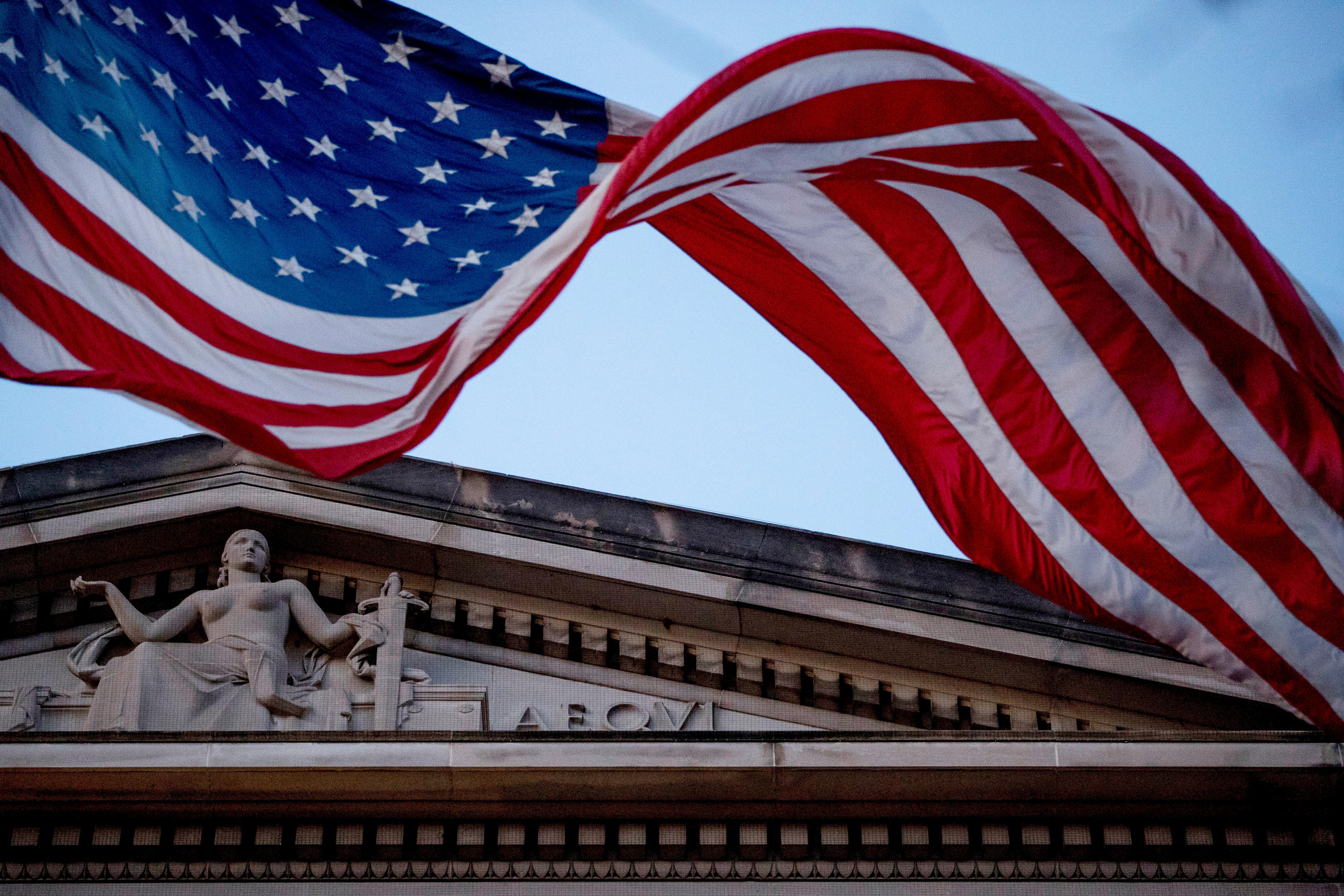 FILE - In this March 22, 2019 file photo, an American flag flies outside the Department of Justice in Washington. The Department of Justice says in a statement that hackers have been attempting to obtain intellectual property and public health data related to vaccines, treatments, and testing. (AP Photo/Andrew Harnik)