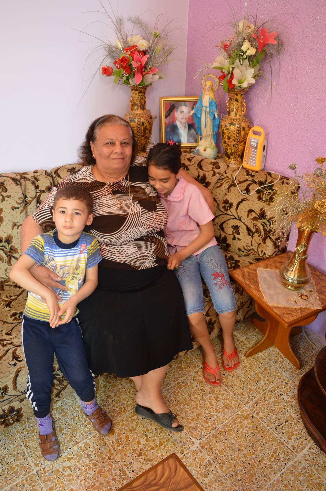 Nazran Aziz med två av sina barnbarn. På fotot i bakgrunden hennes son som blev mördad i de strider som blossade upp efter Saddam-regimens fall. 