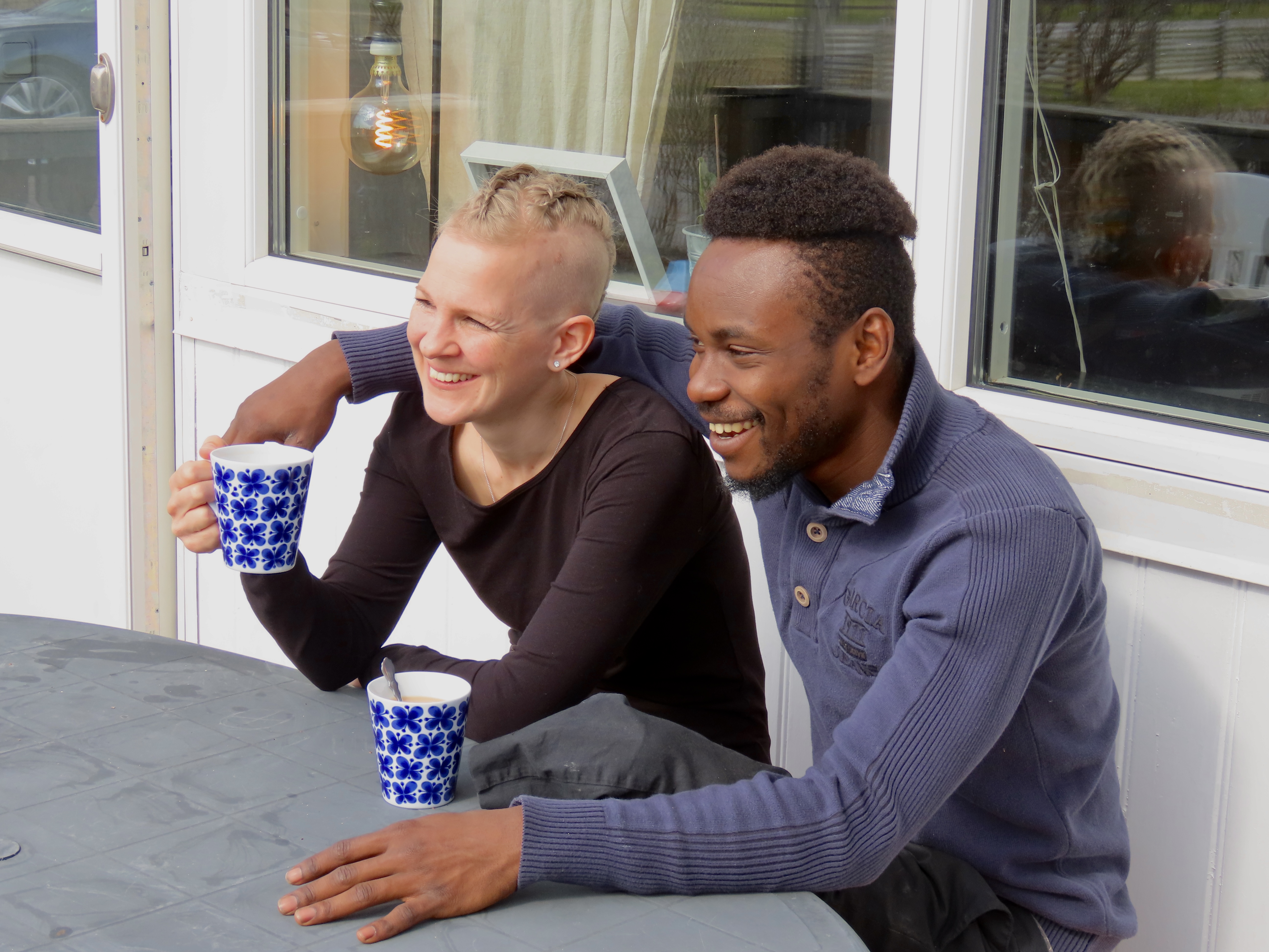 Frida och Nicolas Toto sitter bredvid varandra med varsin kopp i handen.