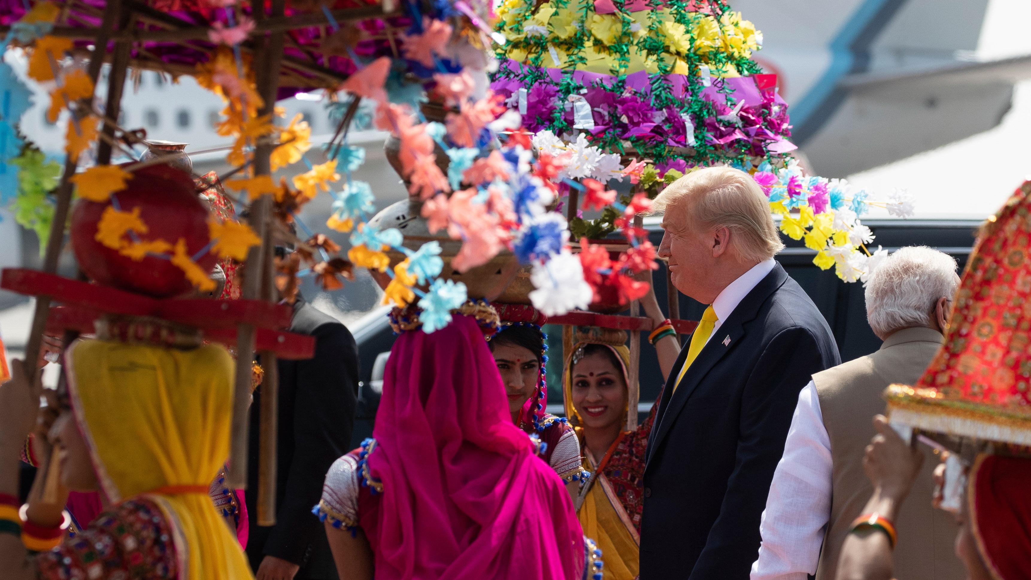 Bildet viser indiske damer kledd i sterke farger. Donald Trump er på besøk.