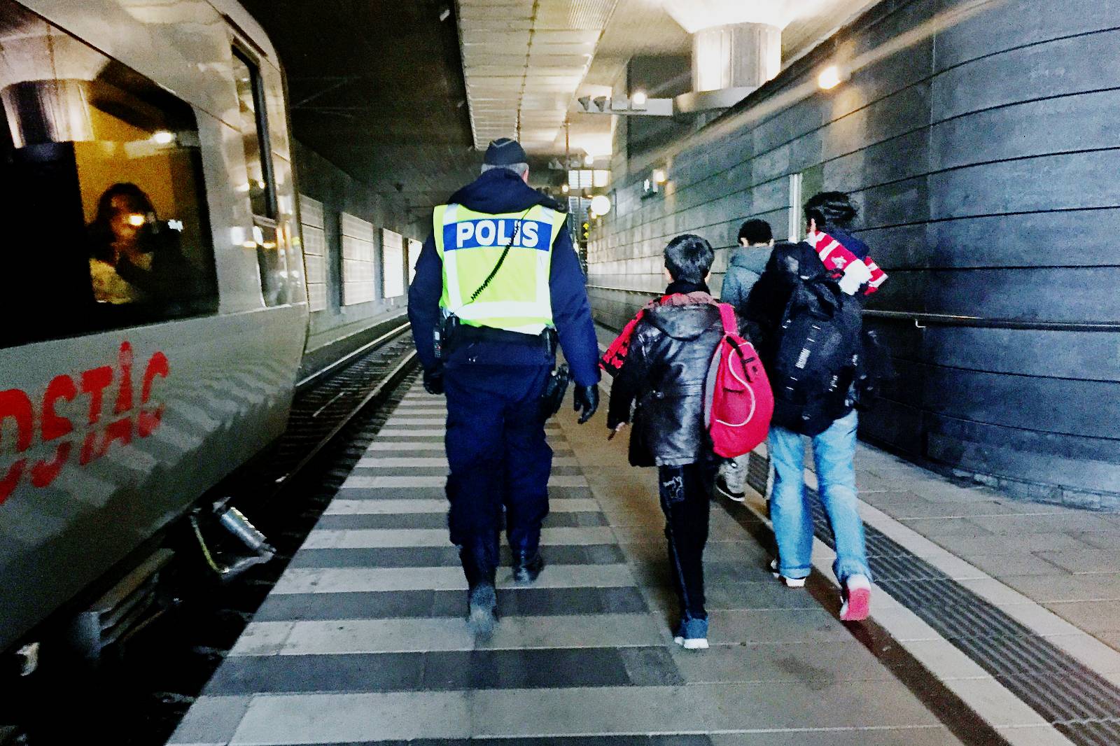 En polis i sällskap med några flyktingbarn som kommit ensamma till Hyllie station i Malmö.