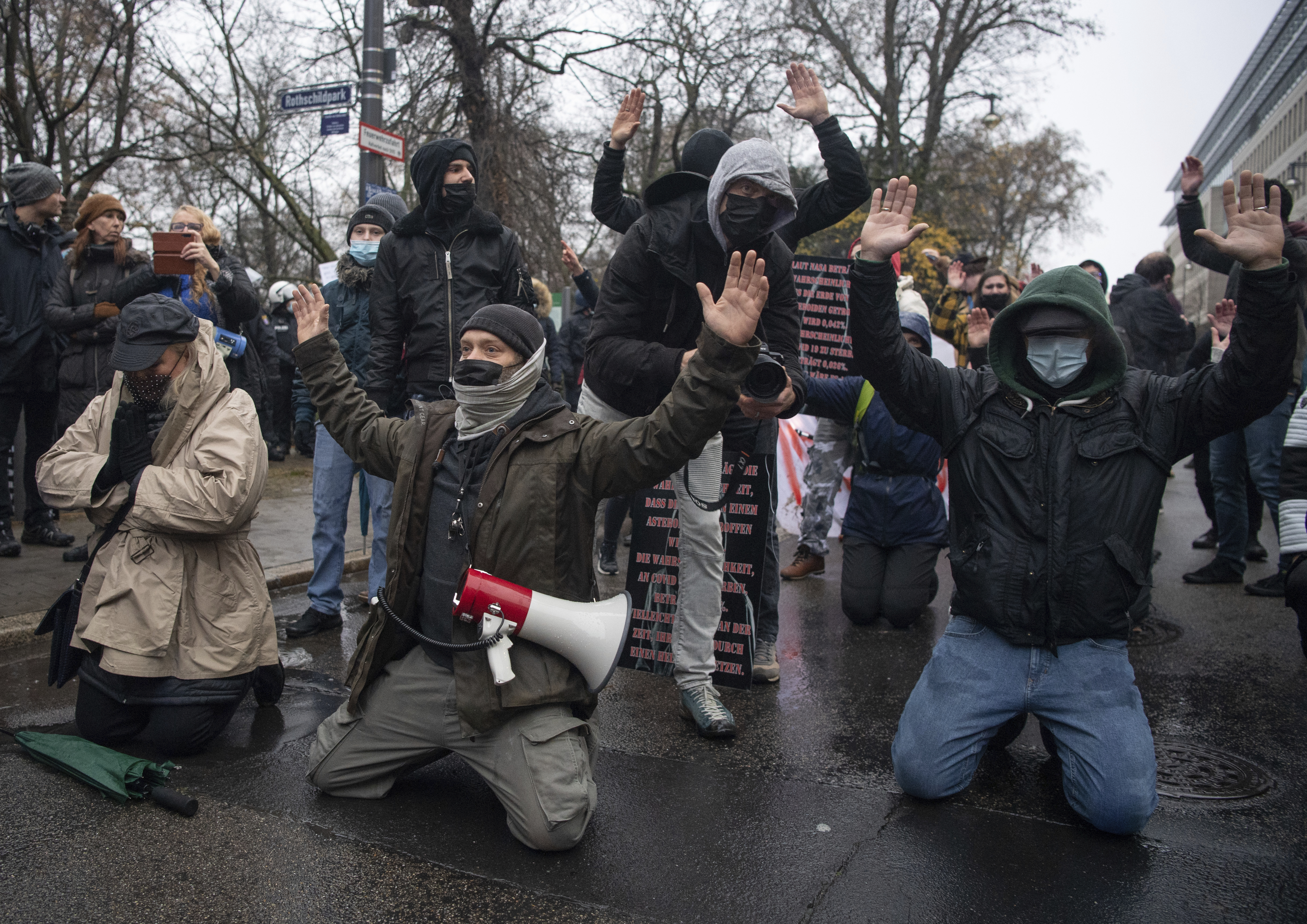 Participants of a demonstration against Corona regulations kneel in front of a police chain with raised arms on the street in Frankfurt, Germany, Saturday, Dec.4, 2021. Several hundred participants, including members of the cross-thinkers and Reichsbürger scene, had gathered in the city center. The police broke up the gatherings. (Boris Roessler/dpa via AP)