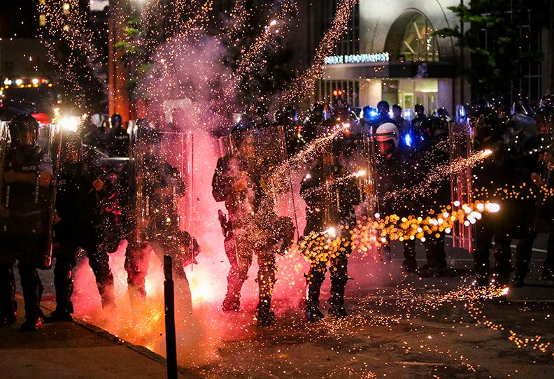 Fireworks go off in front of police, who with protesters in front of police headquarters in St. Louis on Monday, June 1, 2020. The small group of protesters was originally part of a much larger group demonstrating earlier in the afternoon against the death of George Floyd. (Colter Peterson/St. Louis Post-Dispatch via AP)