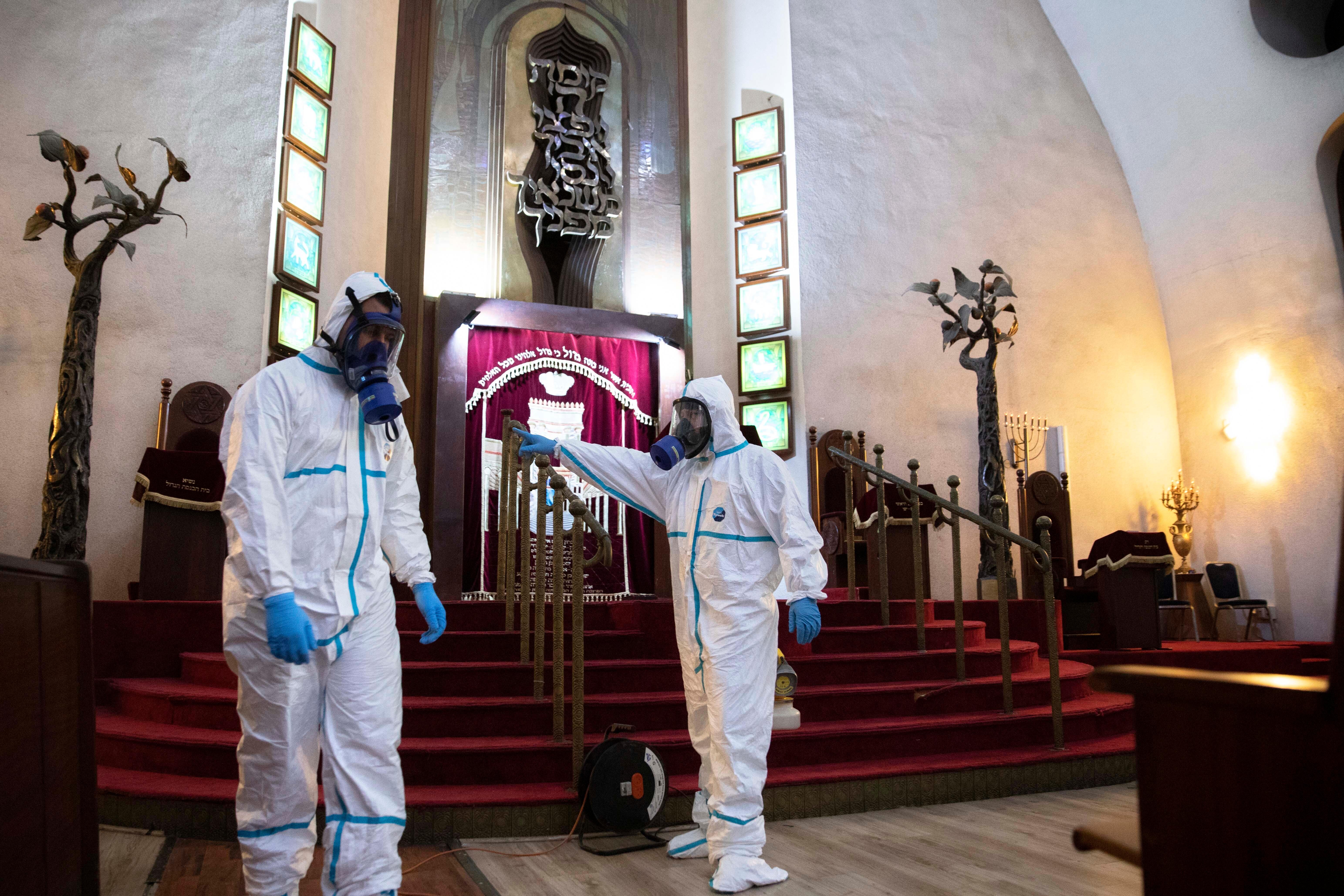Workers sprays disinfectant as a precaution against the coronavirus at the Great Synagogue in Tel Aviv, Israel, Tuesday, March 17, 2020. The head of Israel's shadowy Shin Bet internal security service said Tuesday that his agency received Cabinet approval overnight to start deploying its counter-terrorism tech measures to help curb the spread of the new coronavirus in Israel. For most people, the virus causes only mild or moderate symptoms. For some it can cause more severe illness. (AP Photo/Sebastian Scheiner)