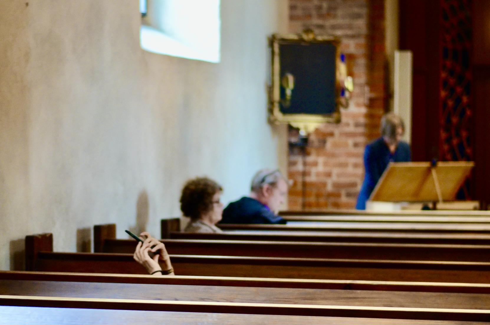 En kvinna tar en bild under konserten. Att ligga i bänken gör att man får syn på det vackra taket i kyrkan.