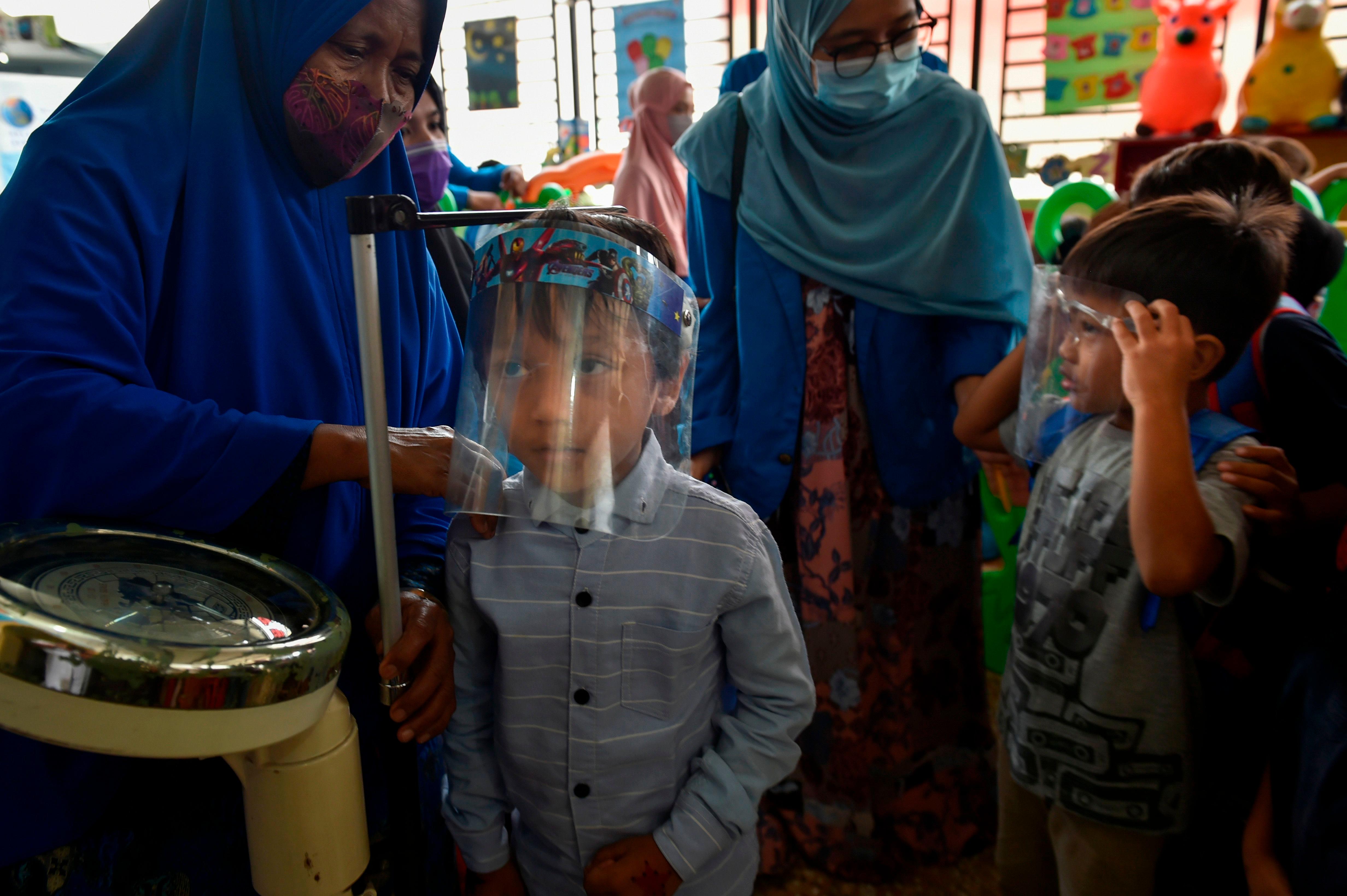 A child's measurements are taken before receiving the measles and polio vaccines at a service post in Banda Aceh on November 4, 2020. (Photo by CHAIDEER MAHYUDDIN / AFP)
