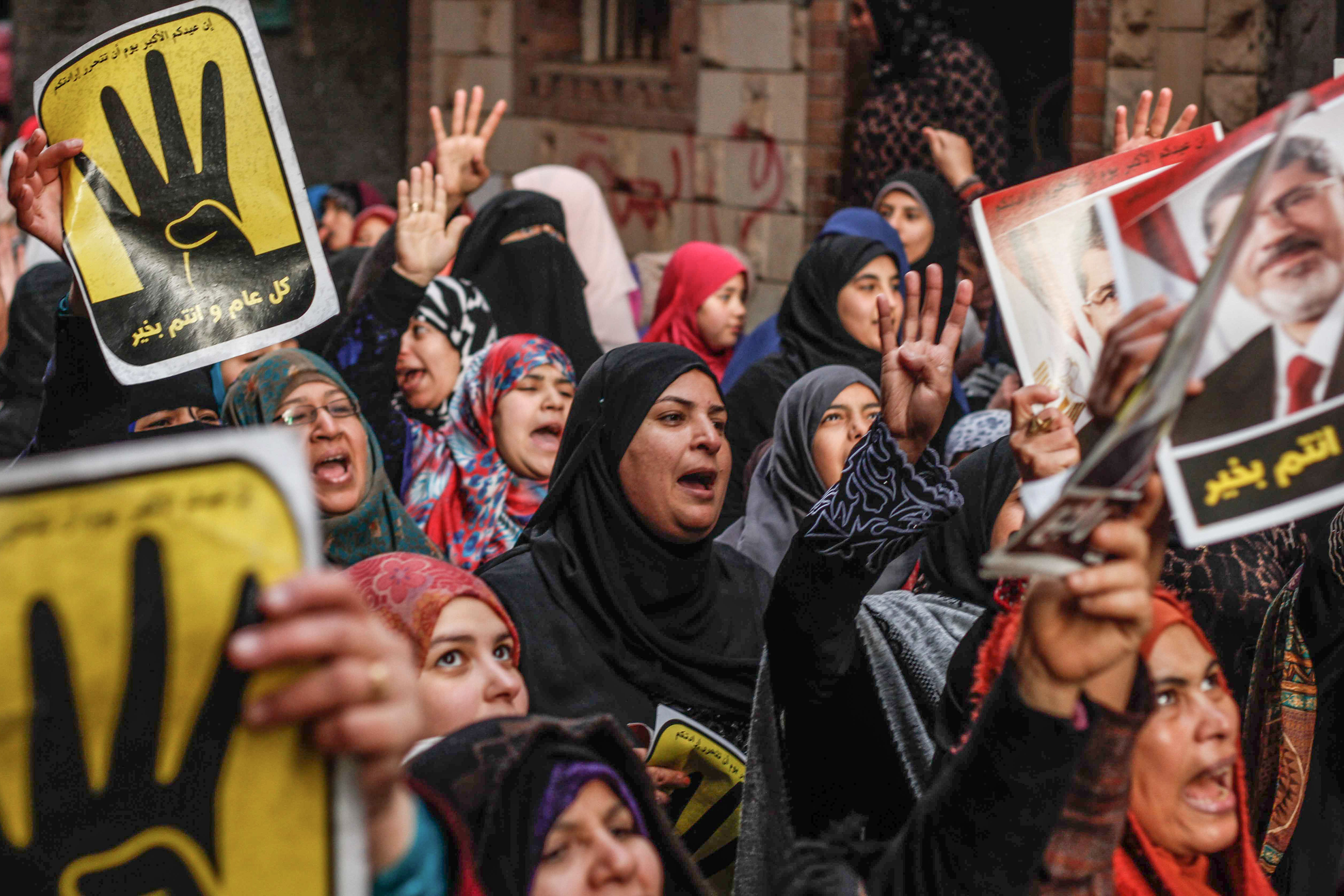 Supporters of the ousted Islamist President Mohamed Morsi chant slogans and raise their hands with a four-fingered anti-government gesture that commemorates the deadly crushing by police of a 2013 Islamist protest camp, in the Faysal district of Cairo, Egypt, Monday, Jan. 25, 2016. The Muslim Brotherhood is the only group who have called on its supporters to take to the streets this Monday, the anniversary of the 2011 uprising that ousted autocrat Hosni Mubarak. Poster reads, "Military rule is a shame and a betrayal." (AP Photo/Hesham Elkhoshny)