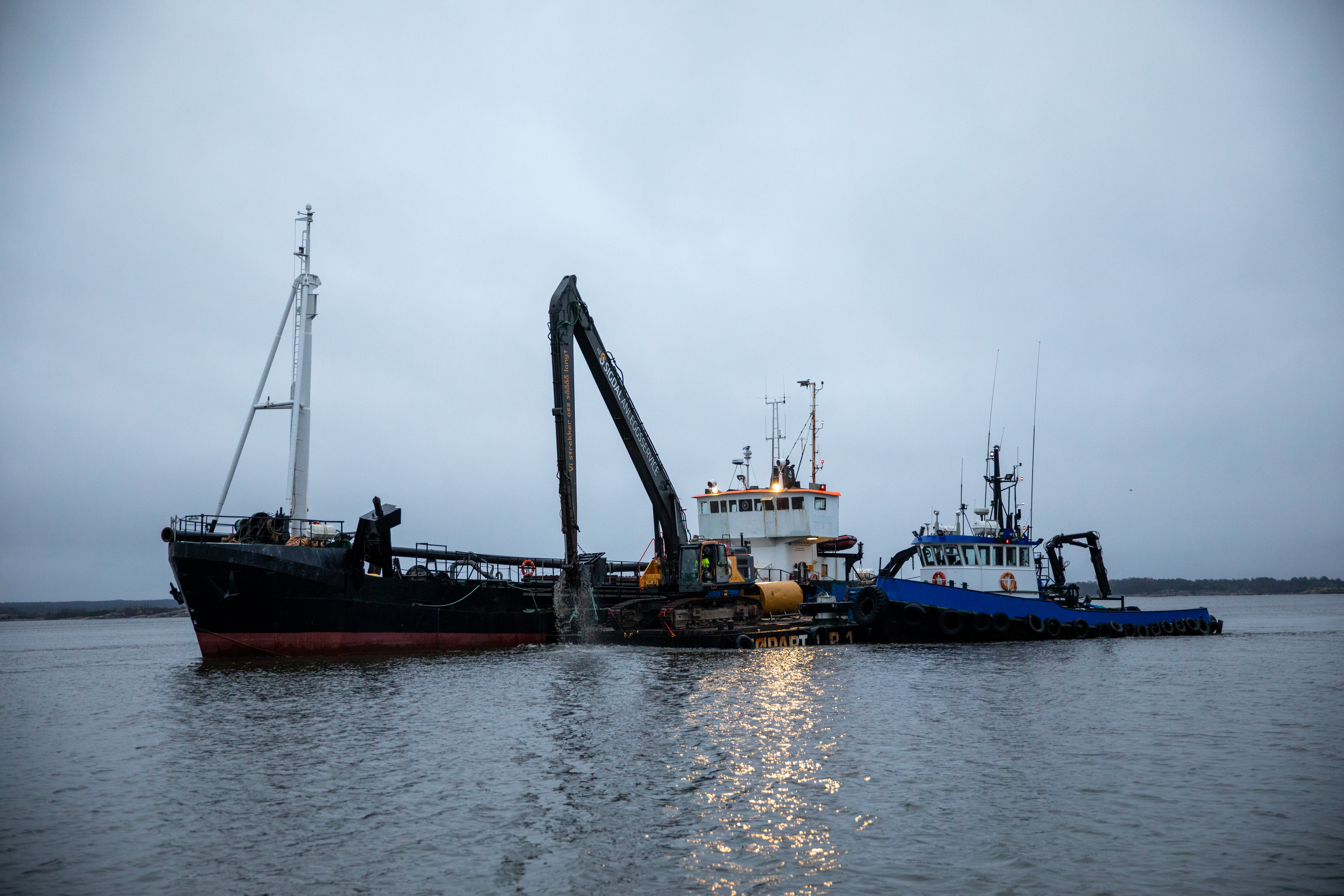 Prøvemudringen er i gang ved Borg Havn. Til arbeidet benyttes en lekter med gravemaskin og grabb.