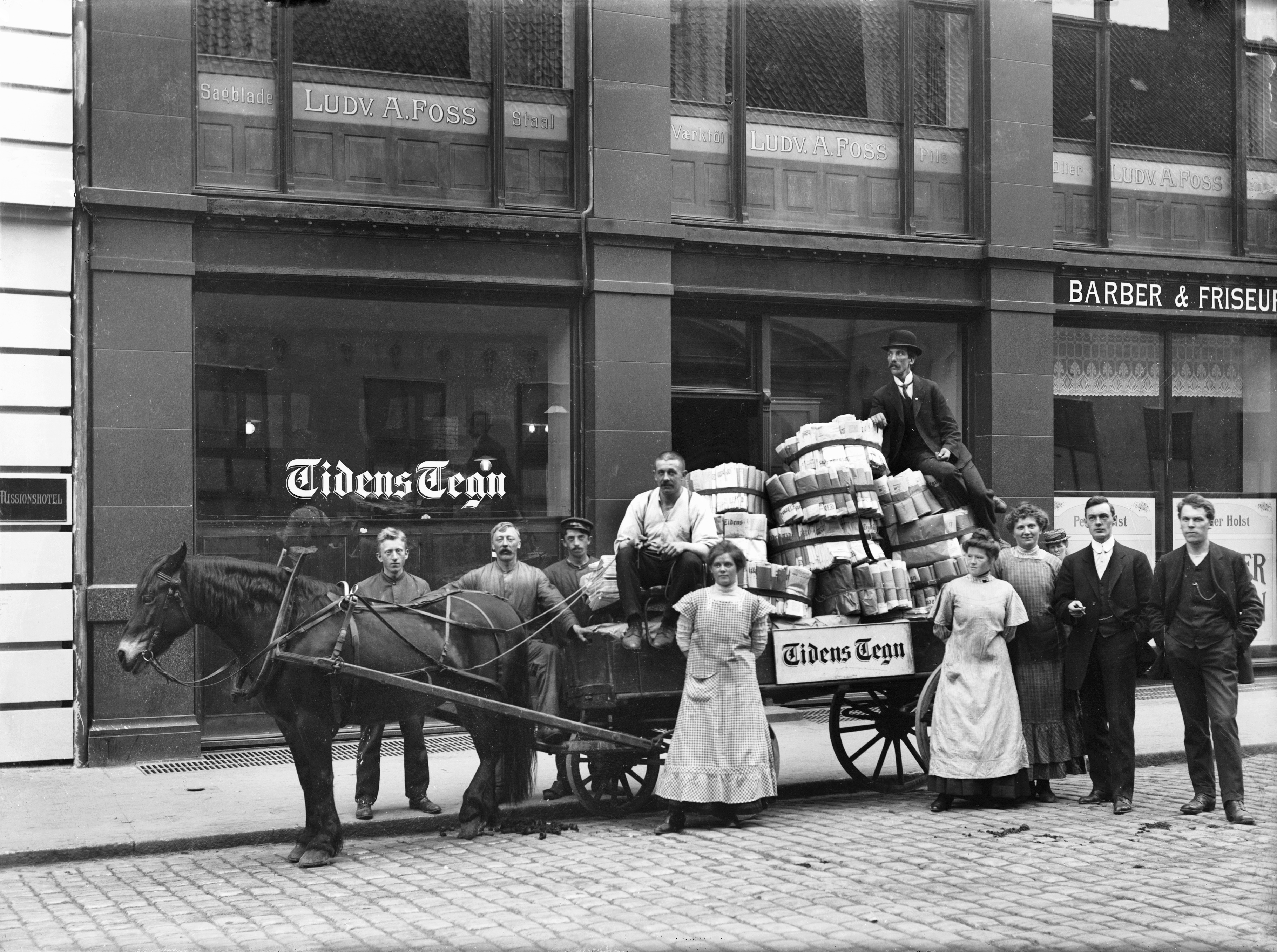 Beskjørtete og buksekledte avisansatte fotografert utafor arbeidsplassen Tidens Tegn i Rådhusgata 20 cirka 1915.