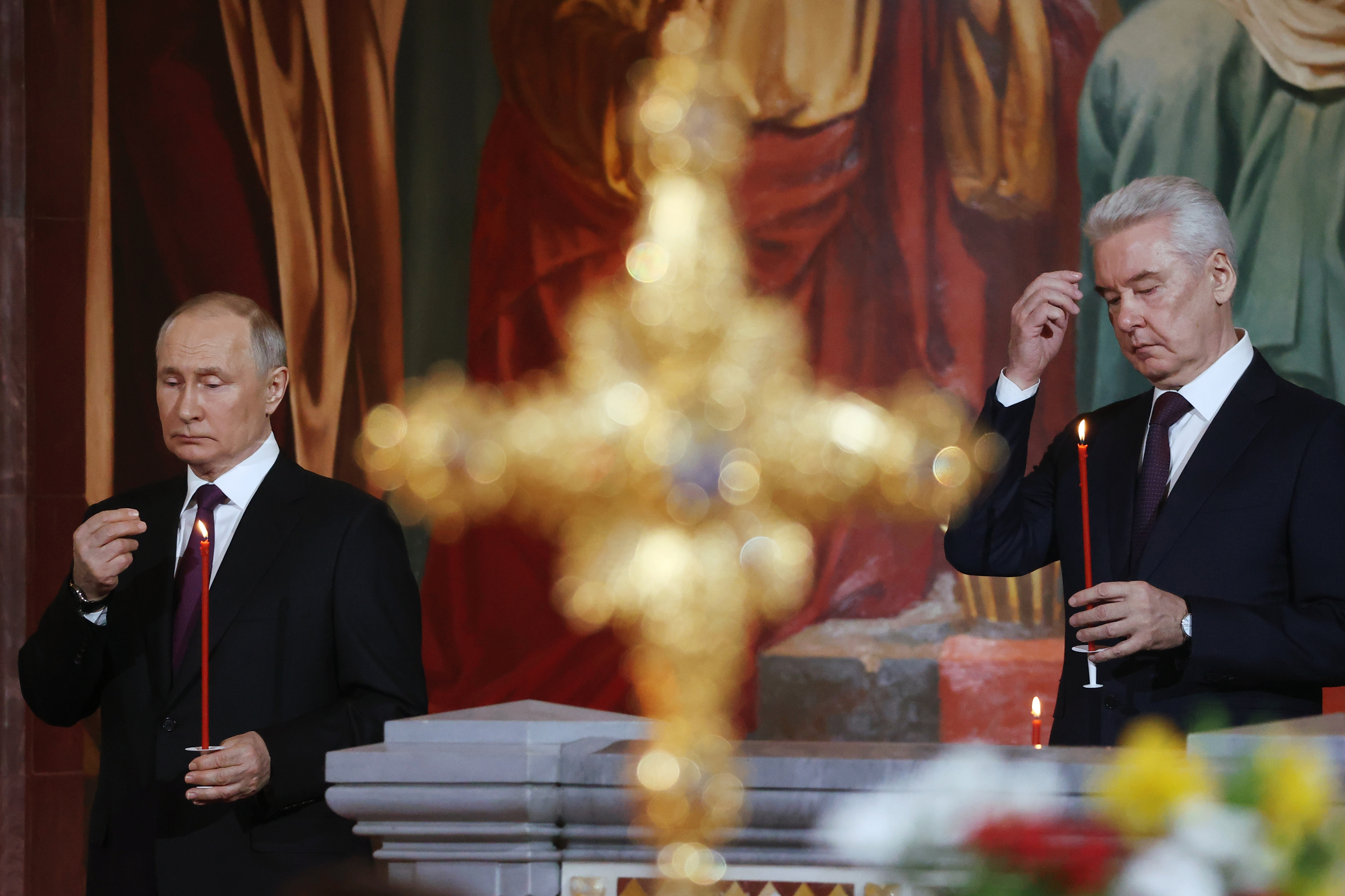 Russian President Vladimir Putin, left, and Moscow's Mayor Sergei Sobyanin make t he sign of the cross during the Orthodox Easter service in the Christ the Savior Cathedral in Moscow, Russia, Saturday, April 15, 2023. (Sergei Karpukhin, Sputnik, Kremlin Pool Photo via AP)