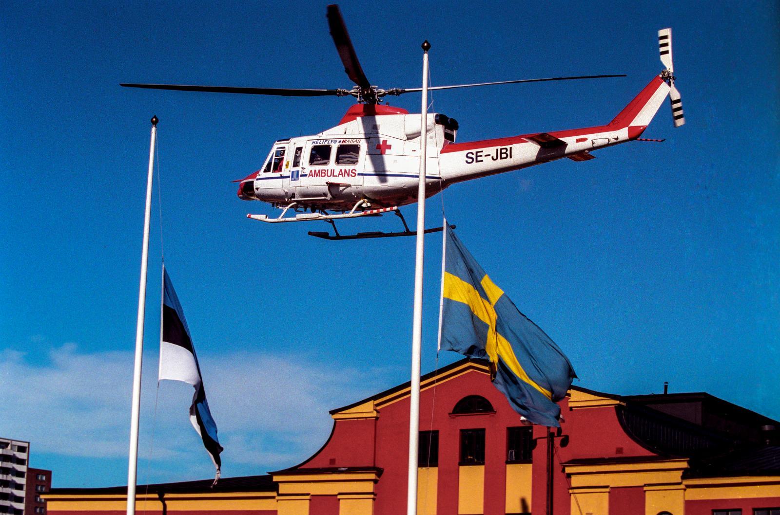 En ambulanshelikopter flyger över Estlines huvudkontor i Frihamnen i Stockholm 28:e september 1994 där estniska och svenska flaggan är hissade på halv stång i samband färjeolyckan M/S Estonias förlisning ute på Östersjön tidigare på natten.
