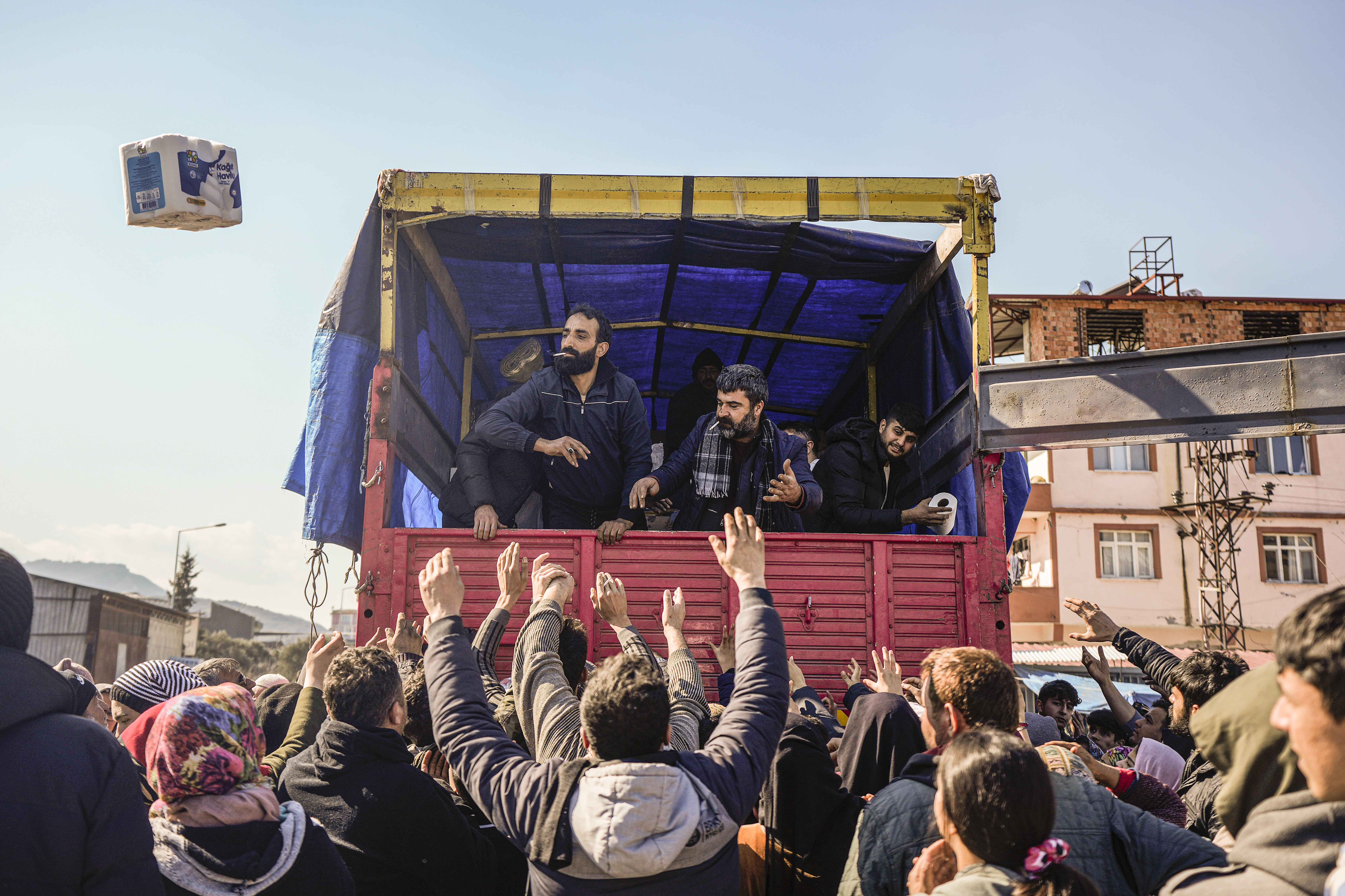 Volunteers distribute aid to people in Antakya, southern Turkey, Wednesday, Feb. 8, 2023. Thinly stretched rescue teams worked through the night into Wednesday, pulling more bodies from the rubble of thousands of buildings downed in Turkey and Syria by a catastrophic earthquake. (AP Photo/Khalil Hamra) KH106