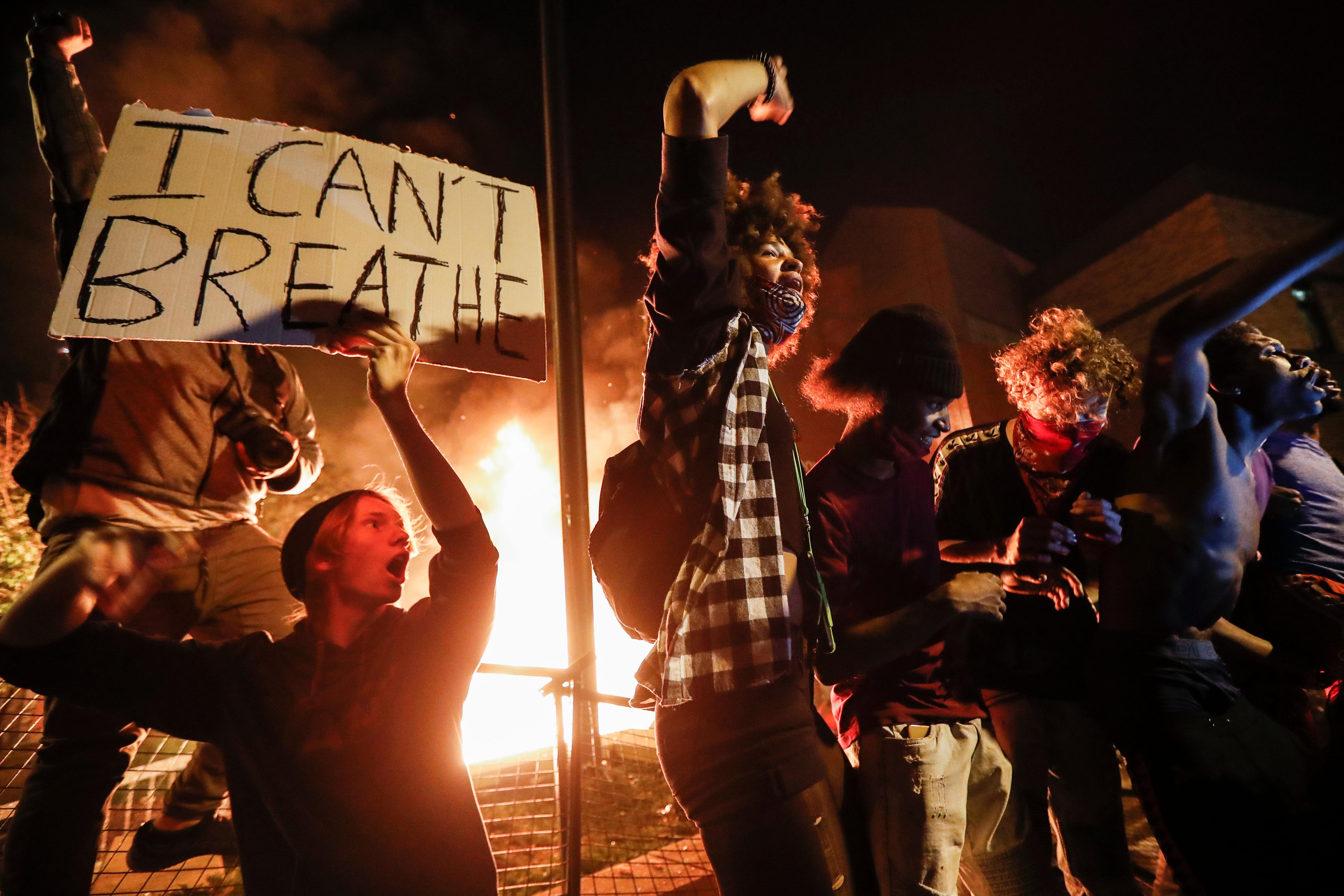 Protestors demonstrate outside of a burning Minneapolis 3rd Police Precinct, Thursday, May 28, 2020, in Minneapolis. Protests over the death of George Floyd, a black man who died in police custody Monday, broke out in Minneapolis for a third straight night. (AP Photo/John Minchillo)