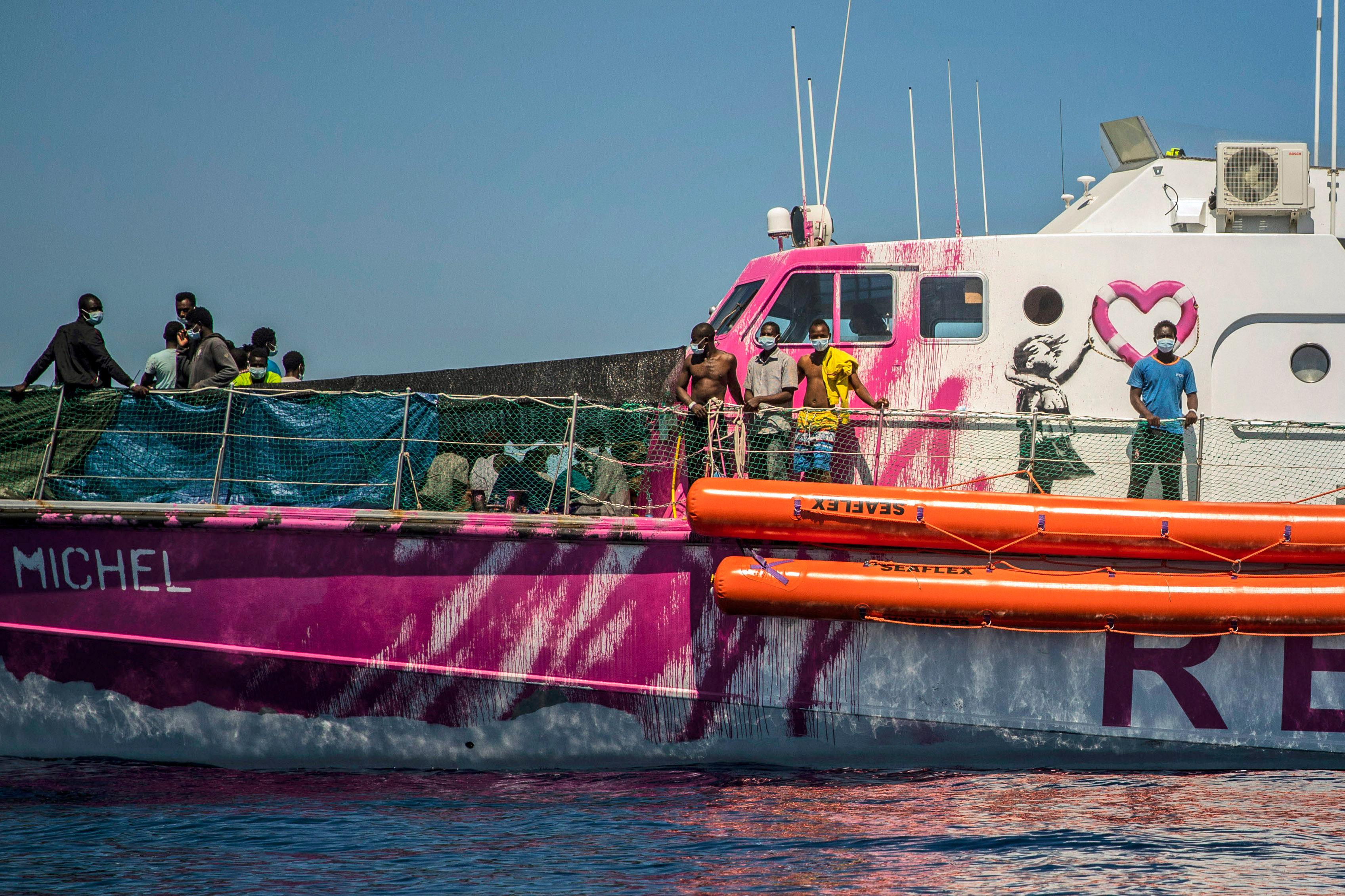 People stand on the deck of the Louise Michel rescue vessel, a French patrol boat currently manned by activists and funded by the renowned artist Banksy in the Central Mediterranean sea, at 50 miles south from Lampedusa, Friday, Aug. 28, 2020. British artist Banksy has financed a boat to rescue refugees attempting to reach Europe from north Africa. (AP Photo/Santi Palacios)