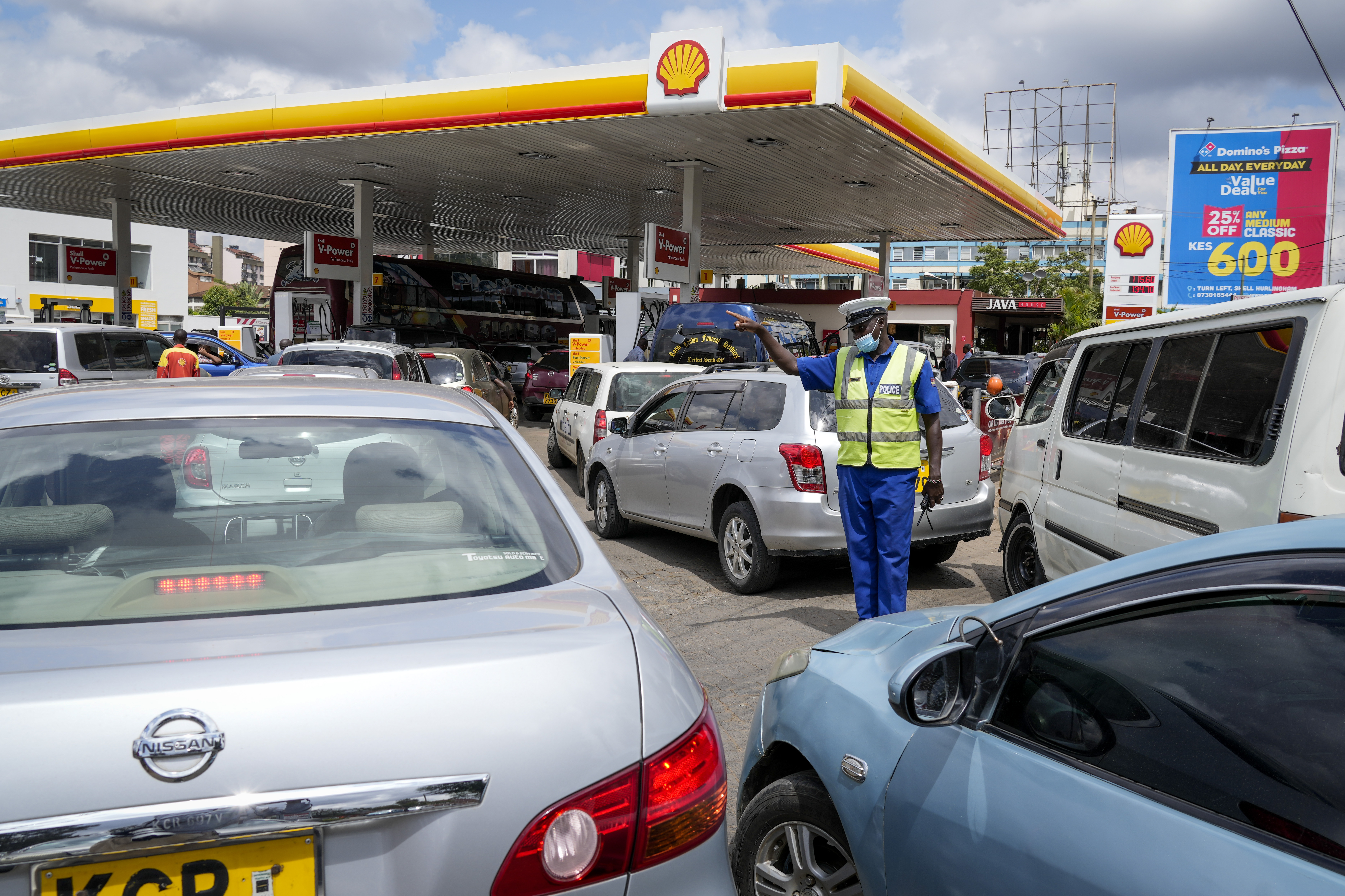 A policeman directs motorists queueing to buy gasoline at one of the gas stations with fuel still available for sale, in the Hurlingham neighborhood of the capital Nairobi, Kenya Thursday, April 14, 2022. For weeks Kenya has been suffering from shortages at gas stations with some having no fuel at all and at others long queues of motorists waiting to be served. (AP Photo/Khalil Senosi)